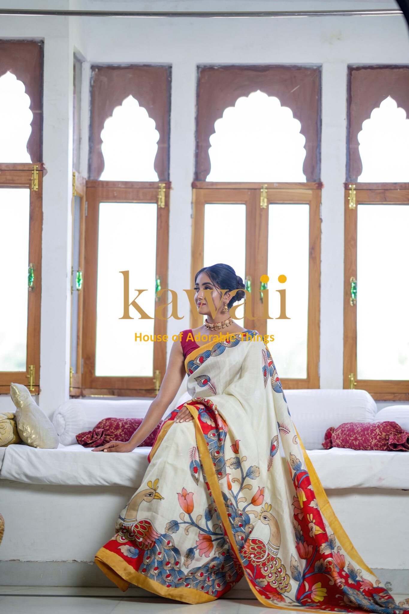 Kawaii kalamkari saree with vibrant floral patterns worn by woman seated indoors