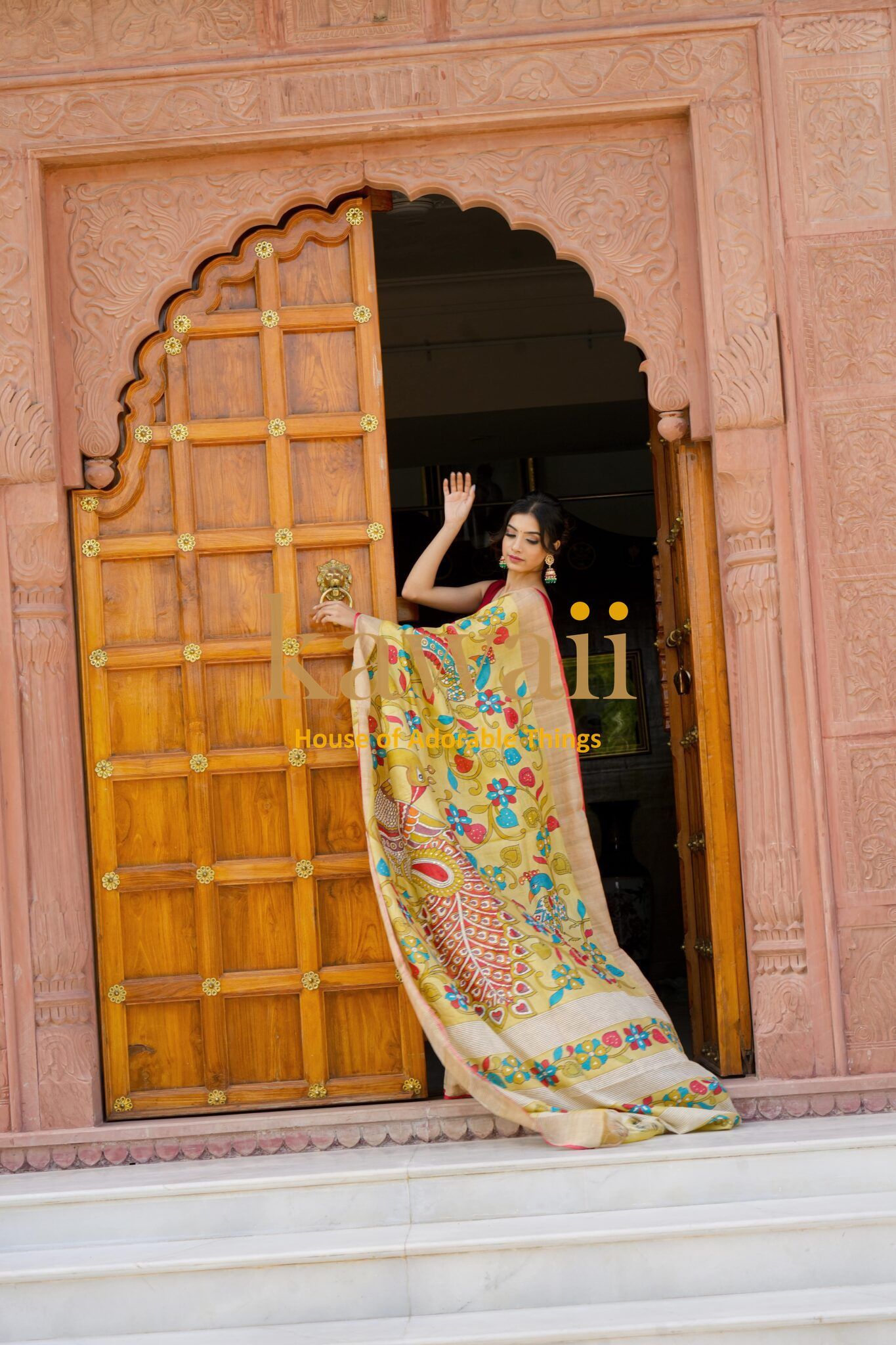 Woman wearing colorful Kawaii kalamkari saree with traditional patterns by a wooden door