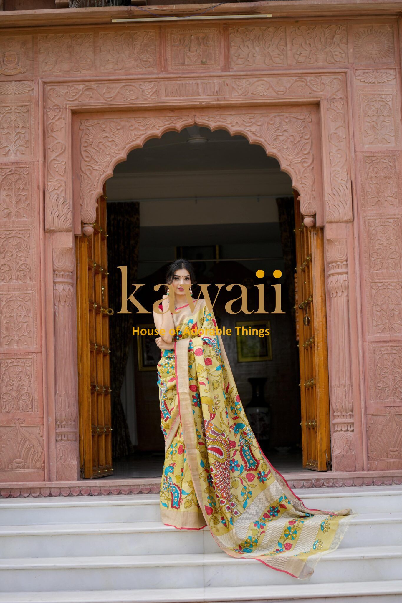 Woman wearing colorful kalamkari saree standing in a traditional carved stone doorway