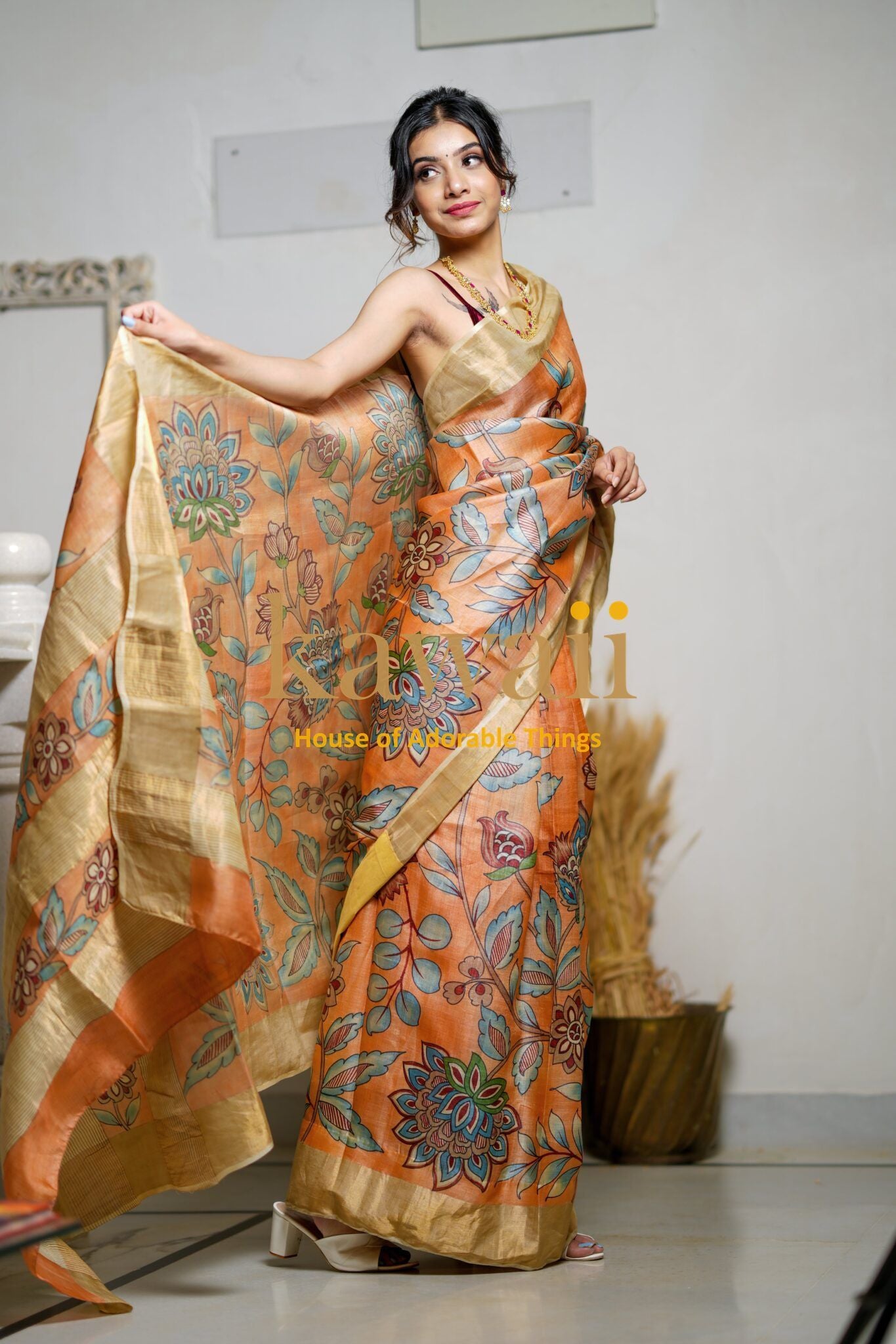 Woman wearing a colorful kalamkari saree with floral patterns and gold border by Kawaii