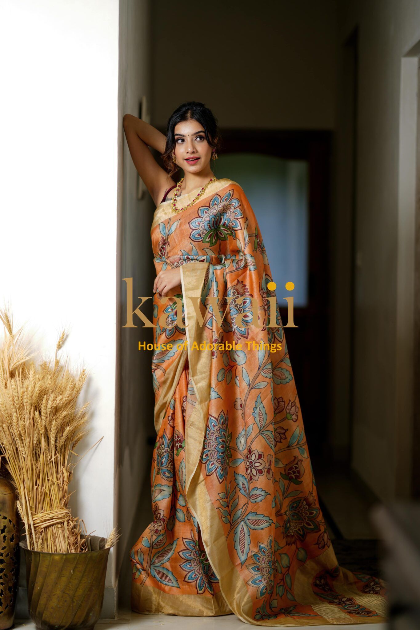 Kawaii kalamkari saree in orange with intricate floral patterns worn by a woman indoors