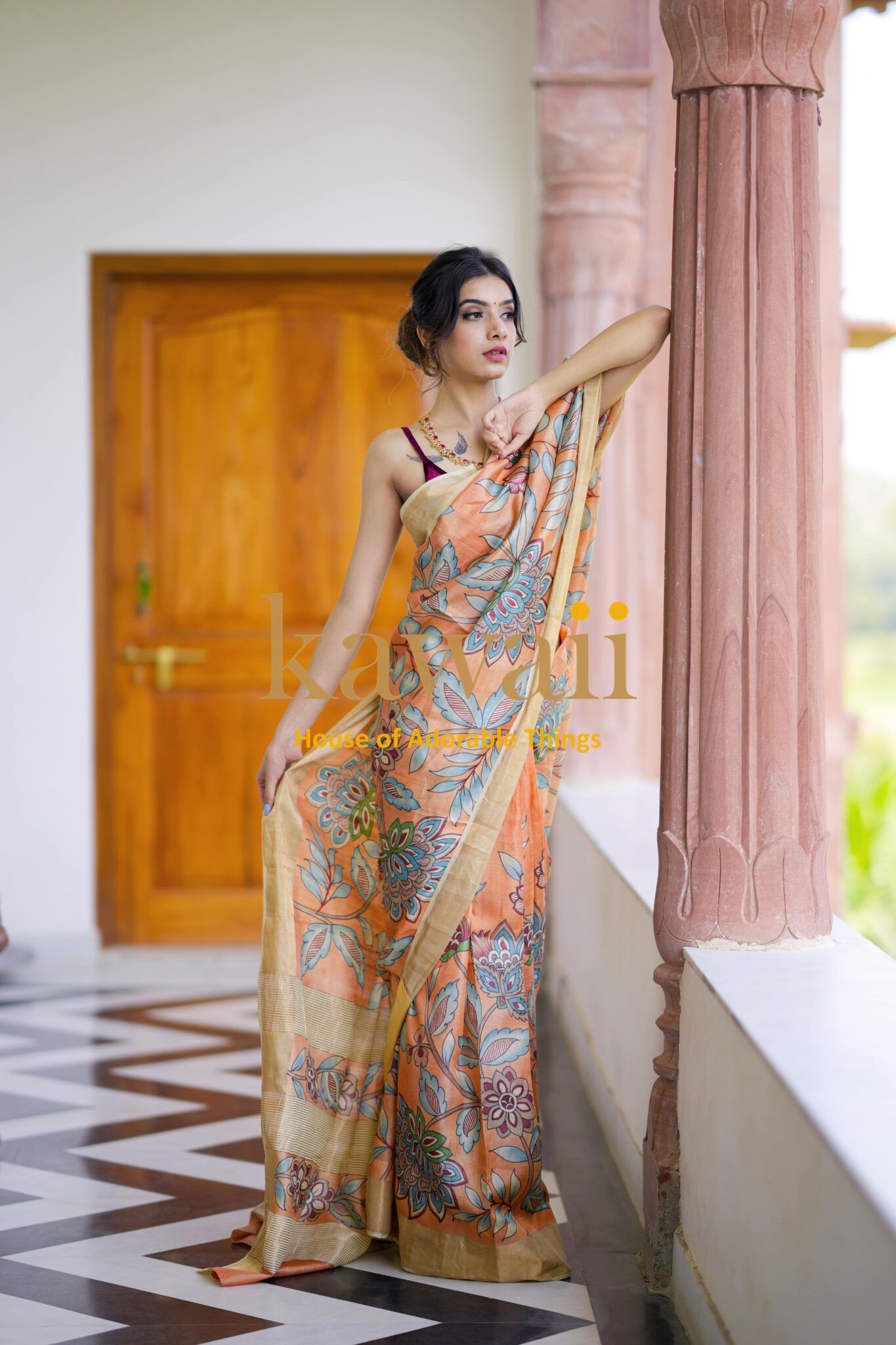 Kawaii kalamkari saree in earthy tones with floral motifs worn by a model on a veranda