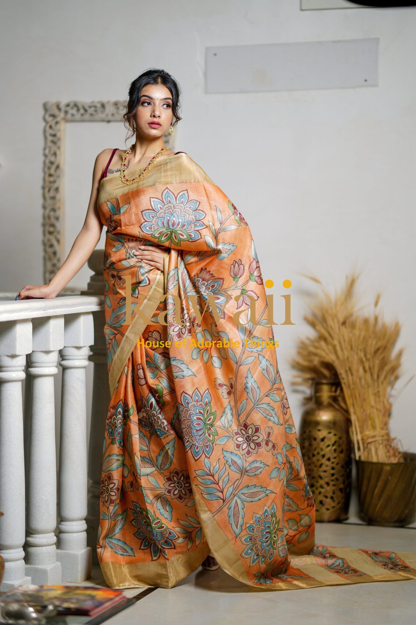 Kawaii kalamkari saree in orange with floral patterns worn by a woman in an indoor setting