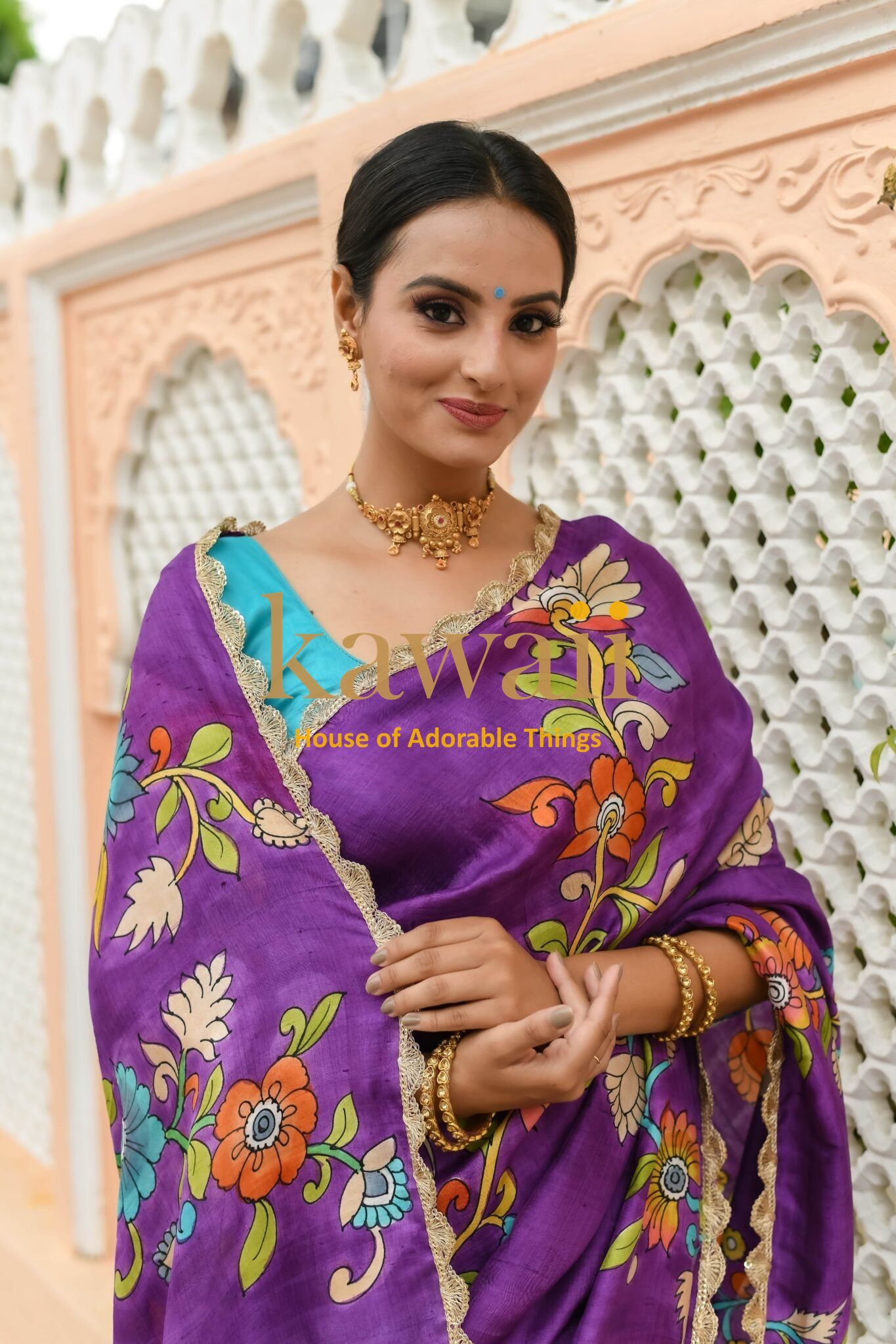 Kawaii purple kalamkari saree with floral patterns worn by a woman with gold jewelry