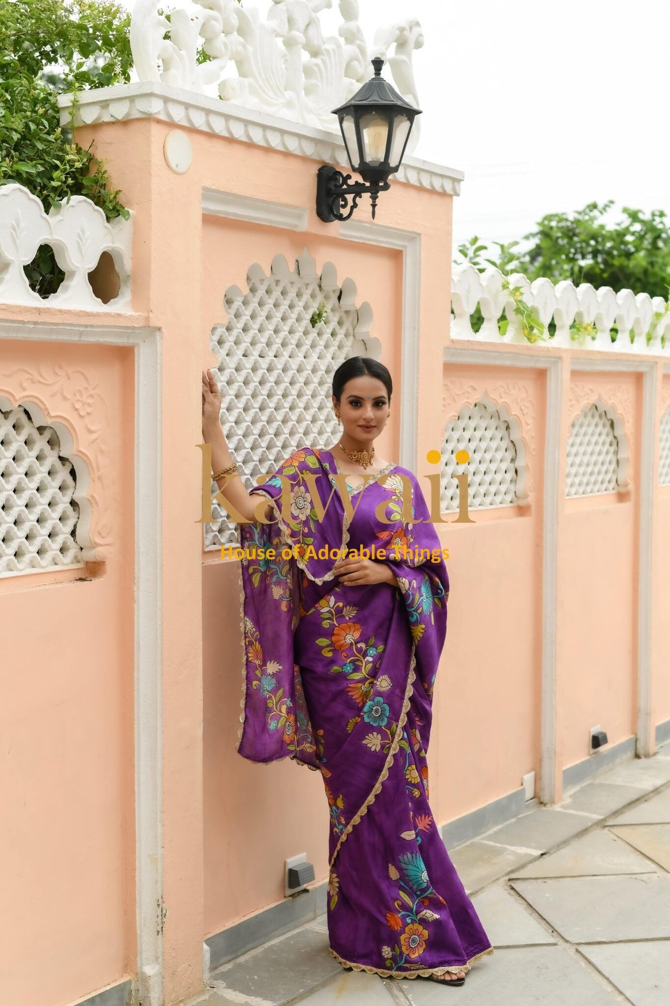 Kawaii purple kalamkari saree with floral prints worn by woman standing against peach wall