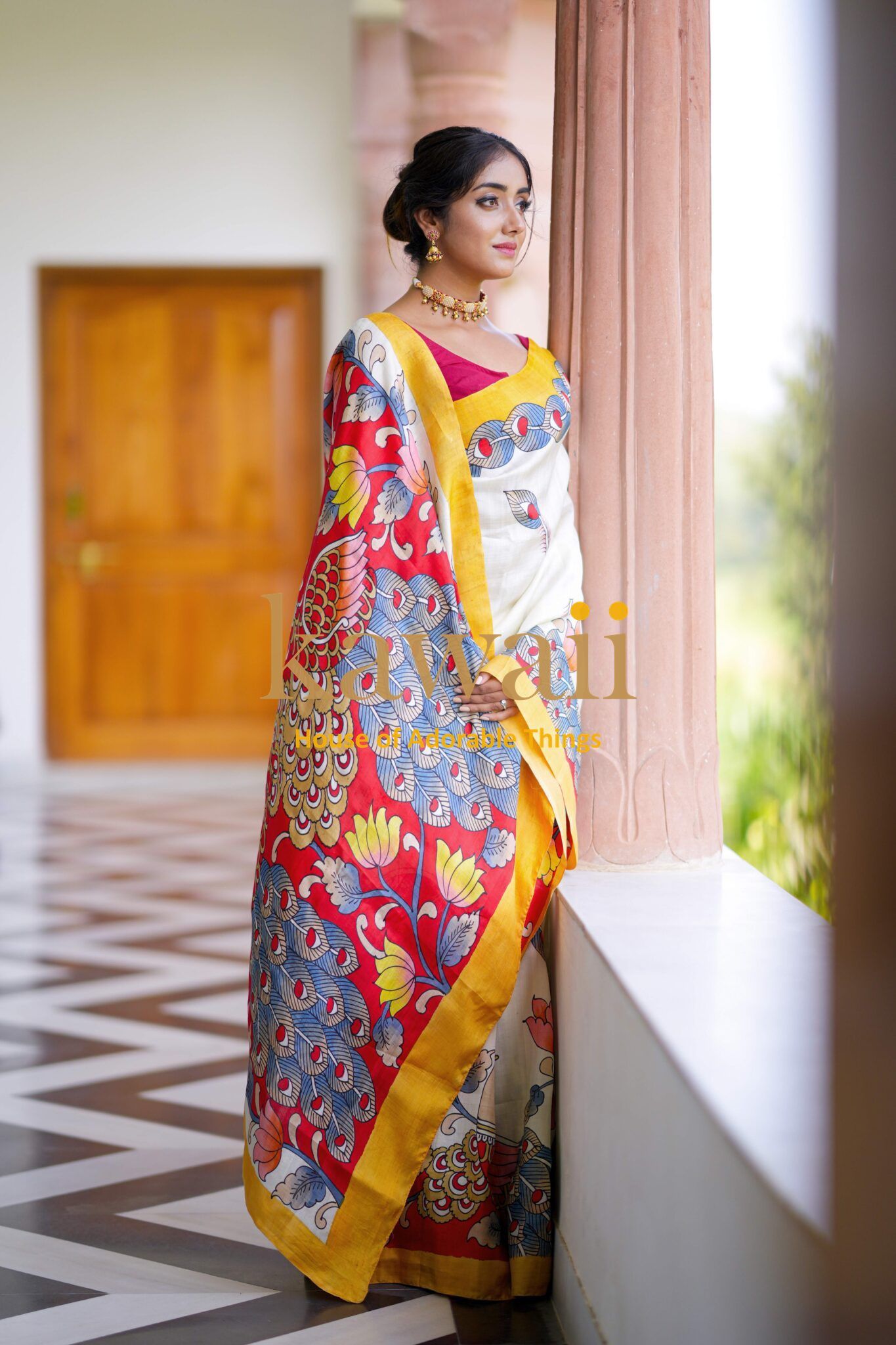 Kawaii kalamkari saree featuring vibrant floral and peacock patterns with yellow border worn by woman indoors