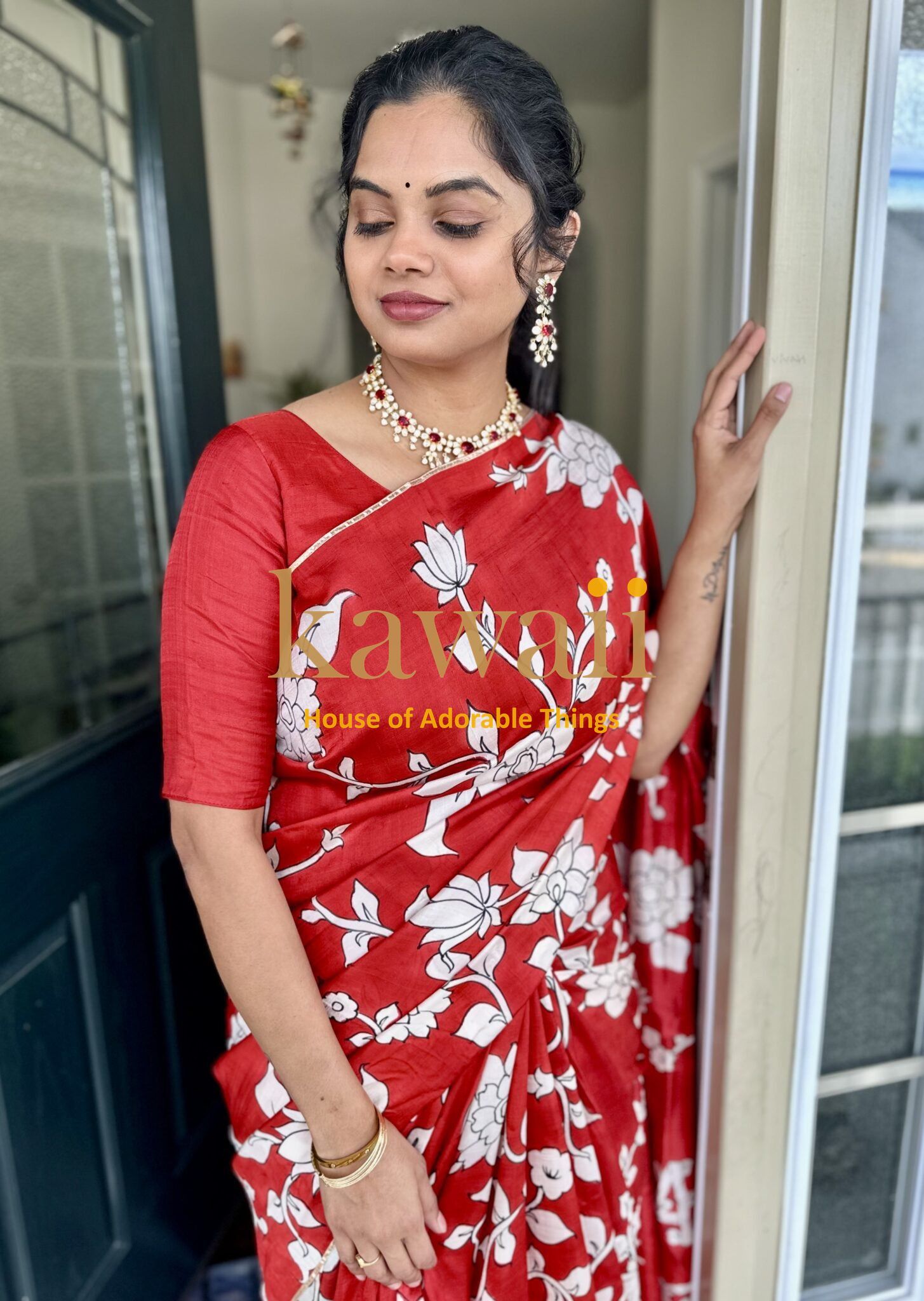 Kawaii red kalamkari saree with white floral patterns worn by woman with traditional jewelry