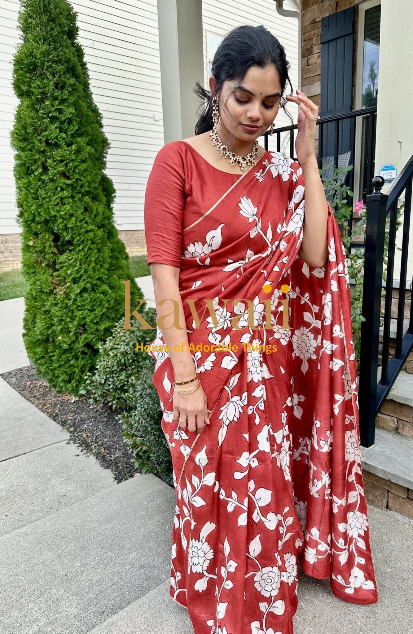 Kawaii red kalamkari saree with white floral design worn by a woman outdoors