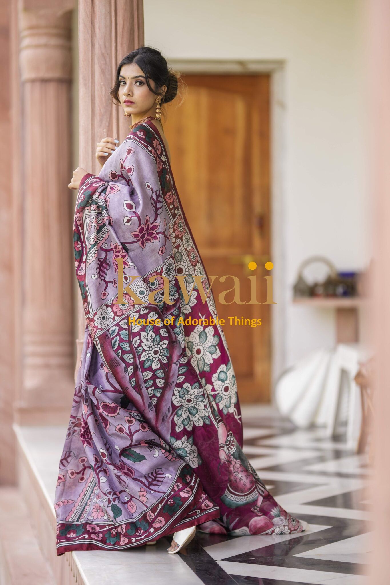 Woman wearing a Kawaii kalamkari saree with intricate floral patterns in purple and maroon shades