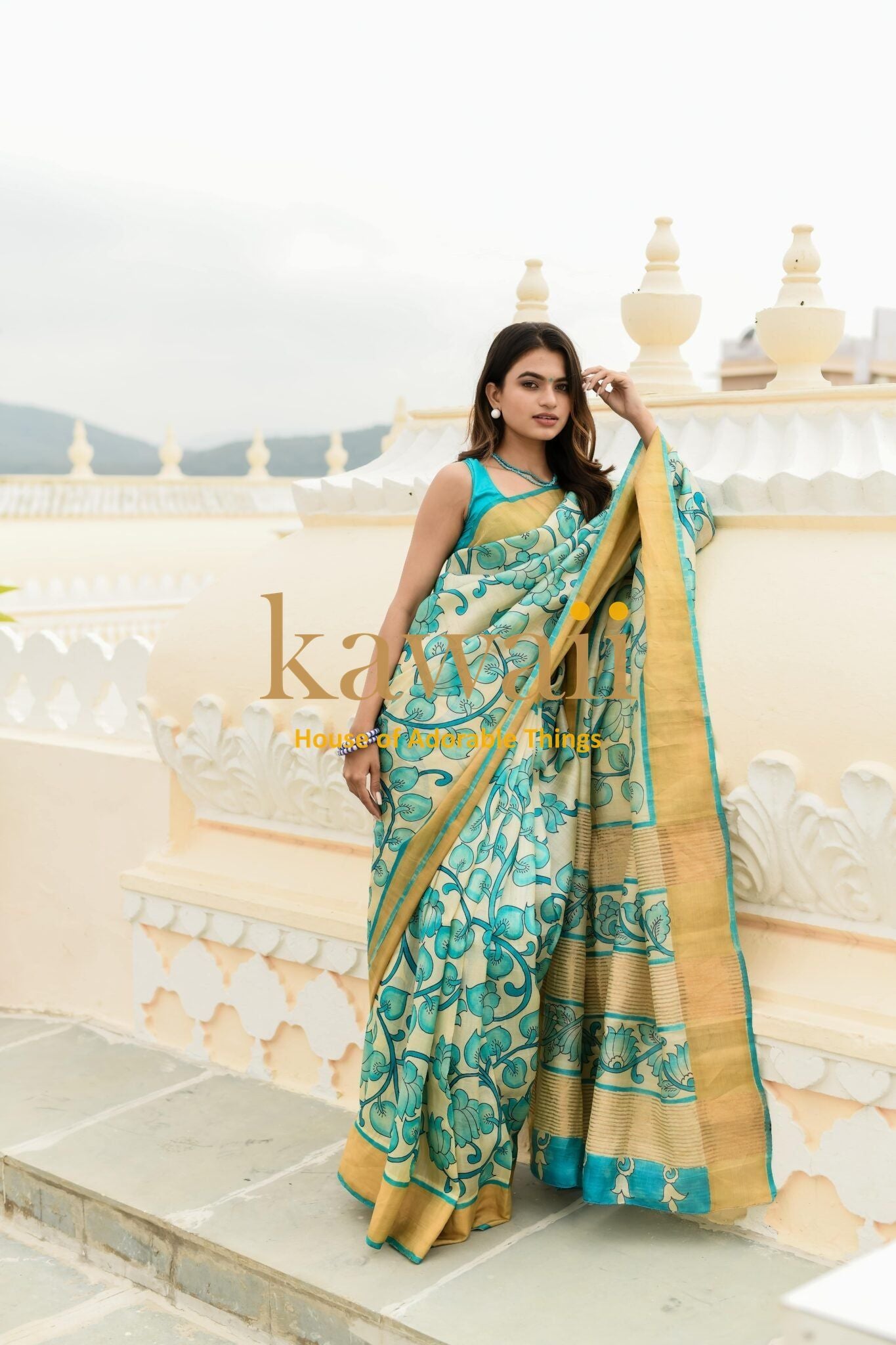 Kawaii kalamkari saree in blue and gold floral design worn by a woman posing outdoors