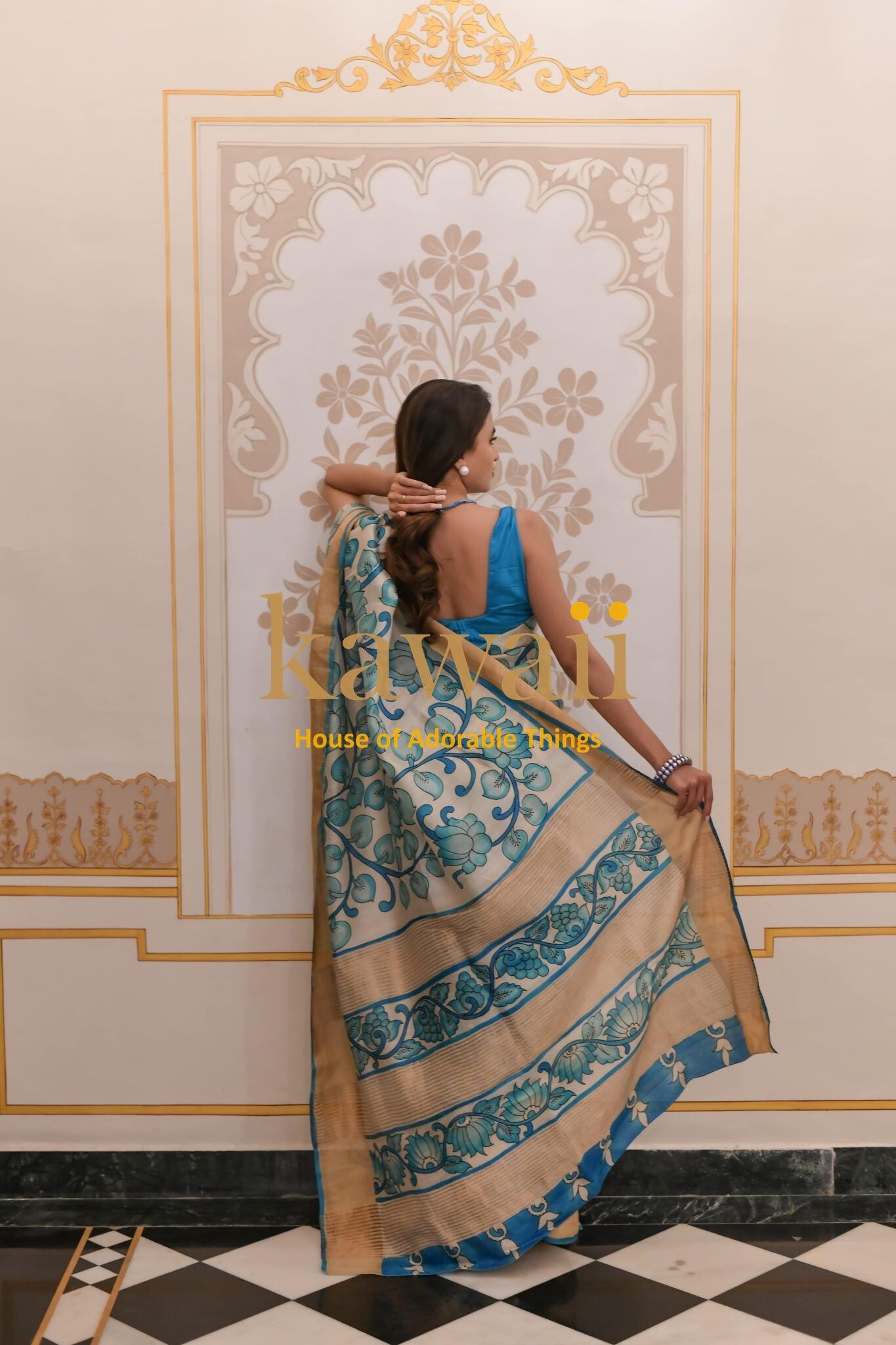 Woman wearing blue and beige Kalamkari saree with floral and paisley patterns by Kawaii