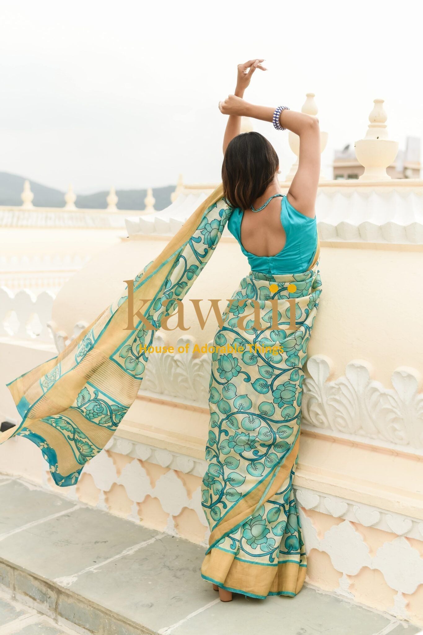 Woman wearing a blue and gold kalamkari saree by Kawaii with intricate floral patterns