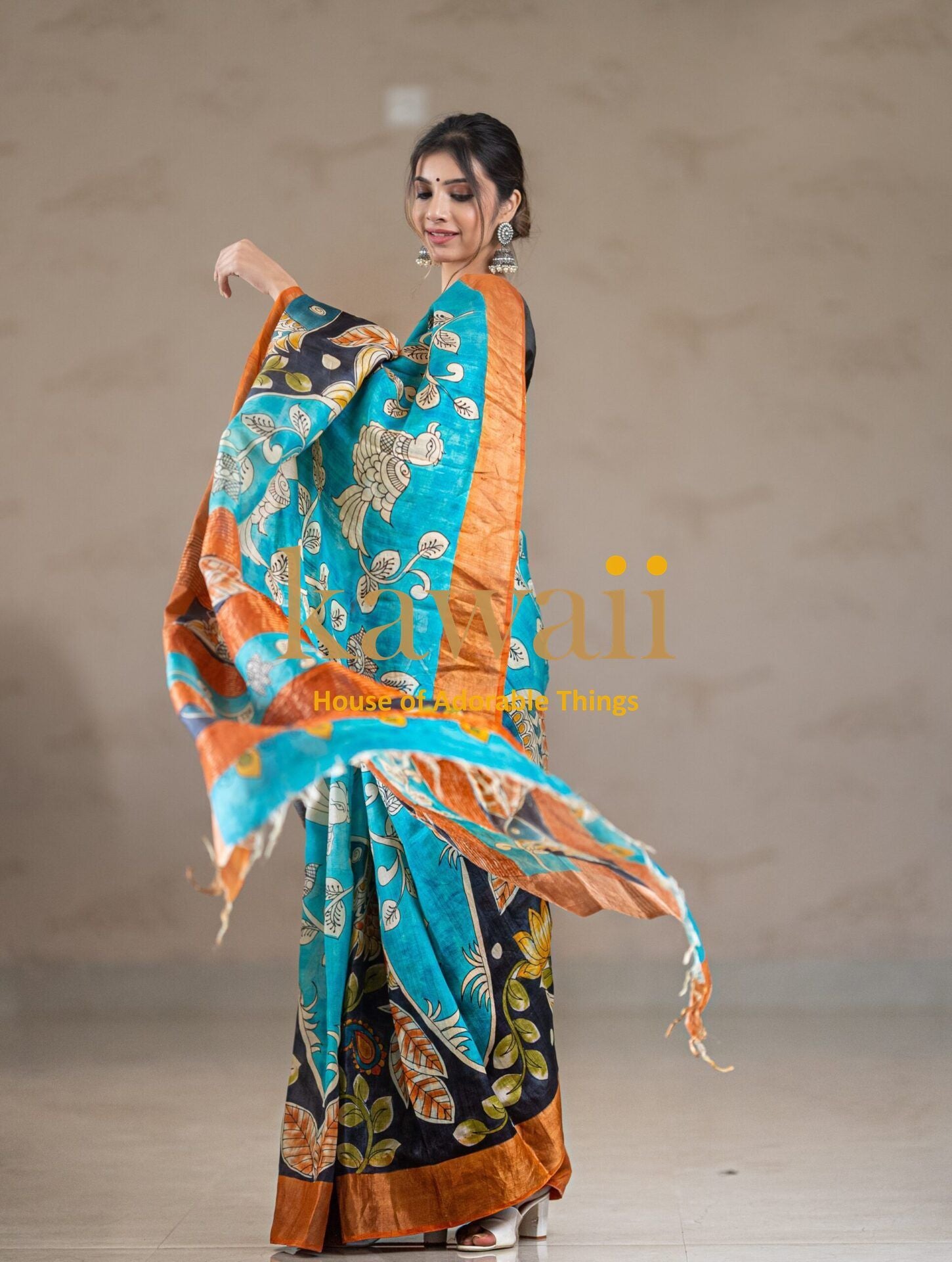 Kawaii kalamkari saree in teal with intricate floral and leaf patterns and orange border worn by model