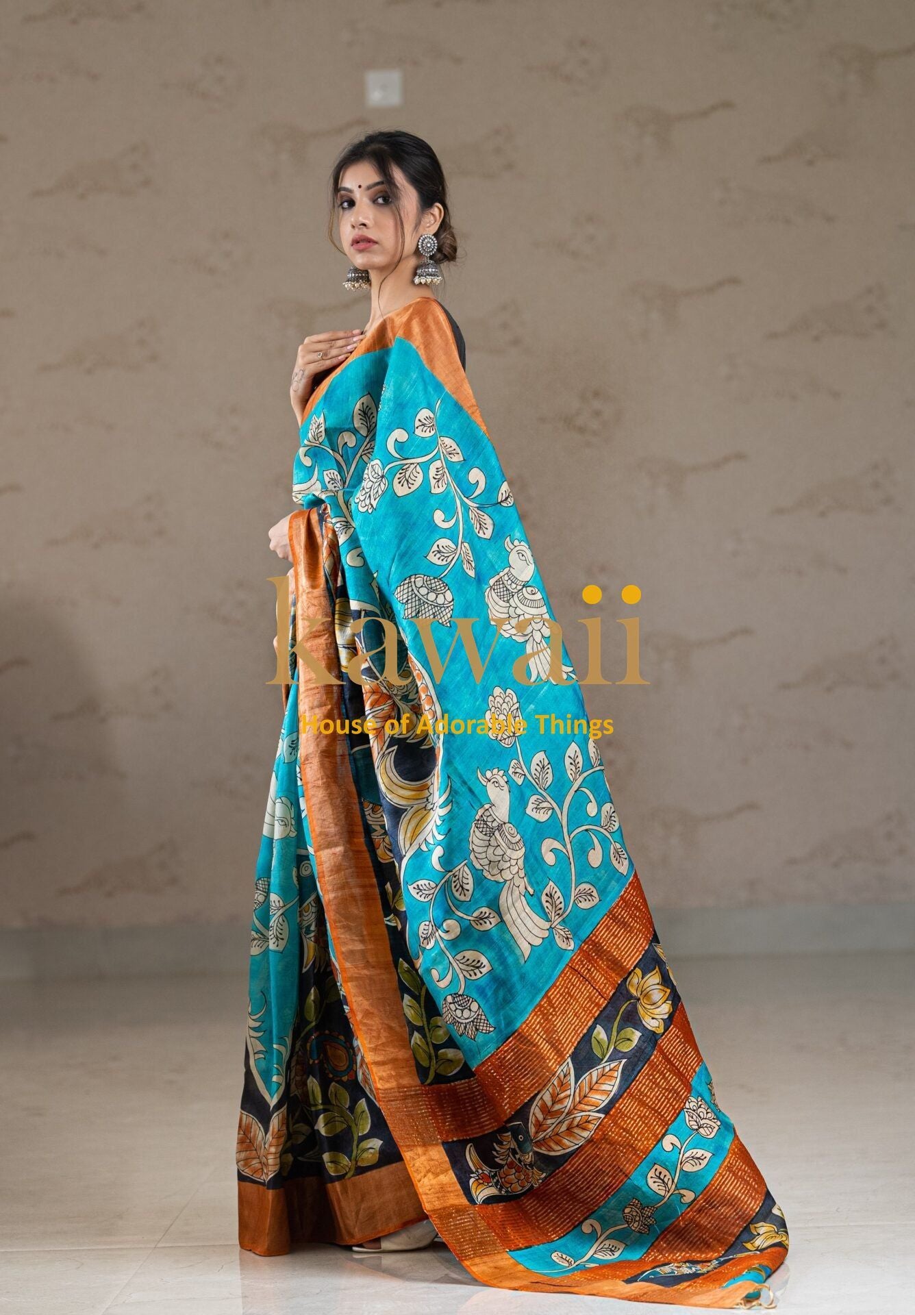 Kawaii kalamkari saree in turquoise with intricate floral and bird motifs and orange border worn by a model