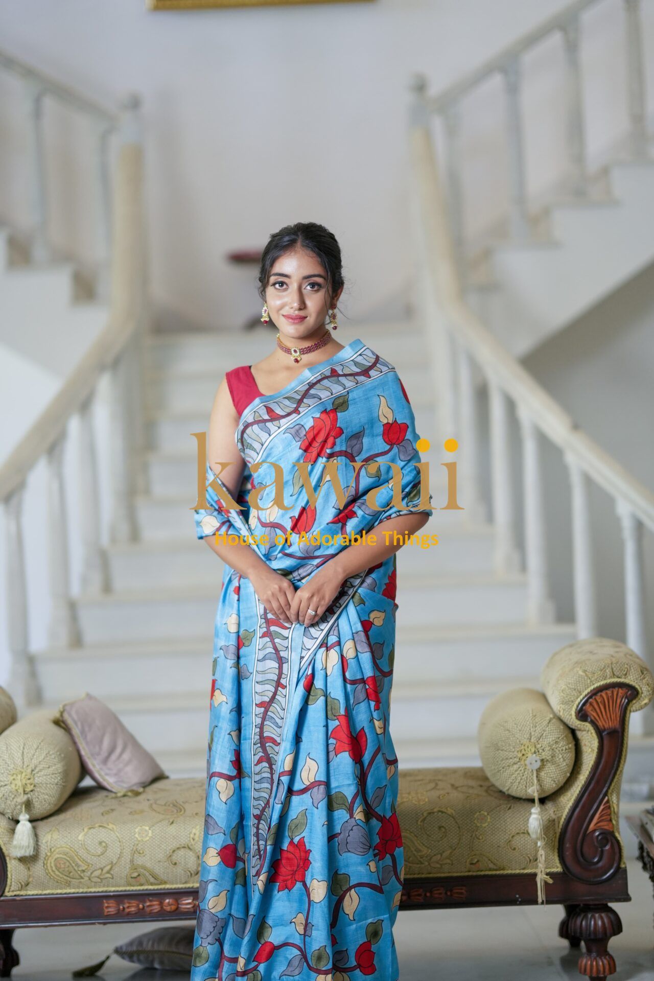Kawaii blue kalamkari saree with red floral patterns worn by woman standing indoors