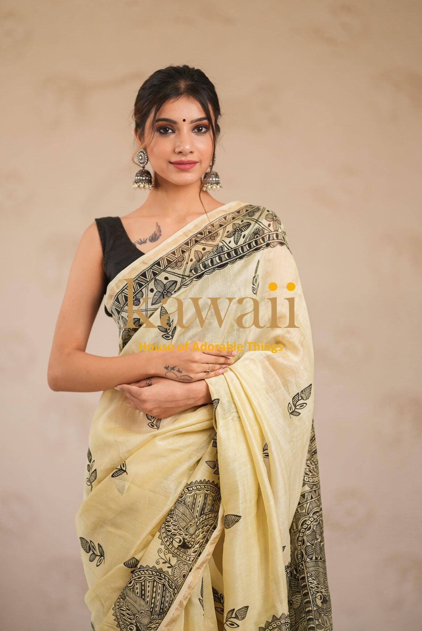 Woman wearing elegant beige and black Madhubani saree with traditional motifs and black blouse