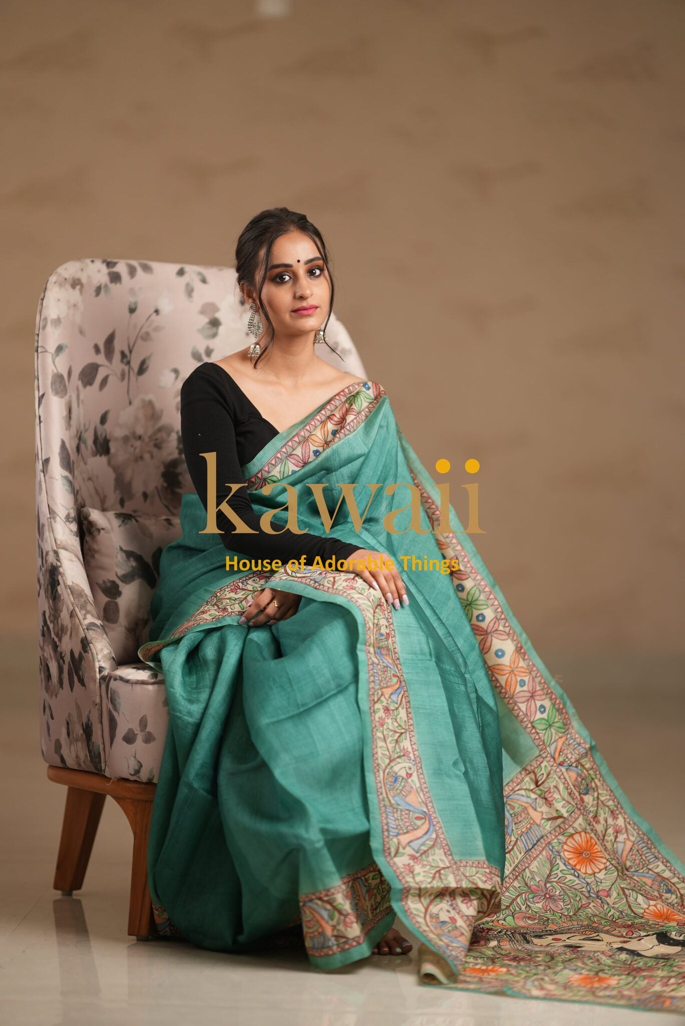 Woman seated wearing a green madhubani saree with intricate traditional border designs