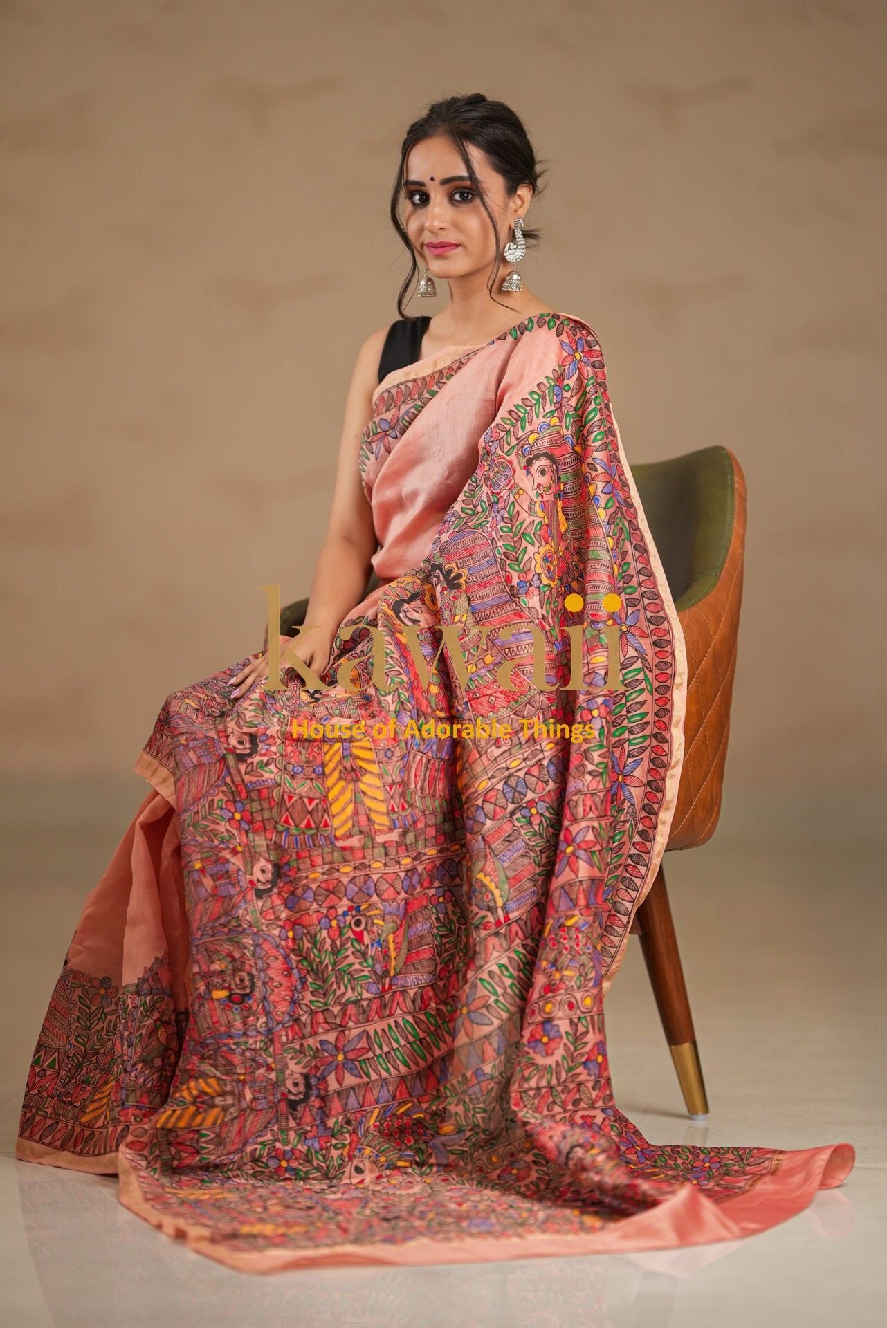 Kawaii madhubani saree with intricate traditional artwork worn by a woman seated on a modern chair