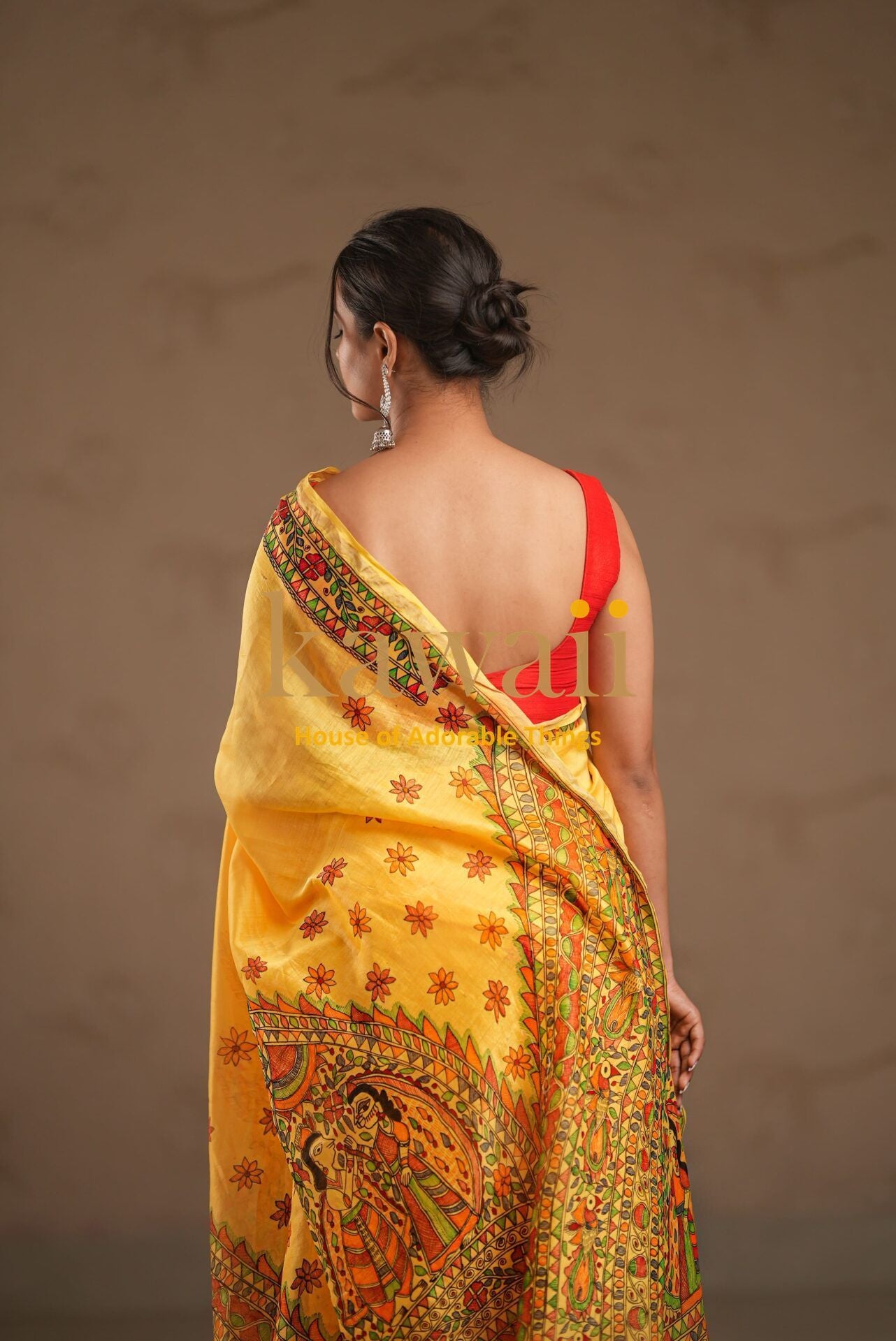 Kawaii yellow madhubani saree with intricate traditional artwork worn by woman with back facing camera