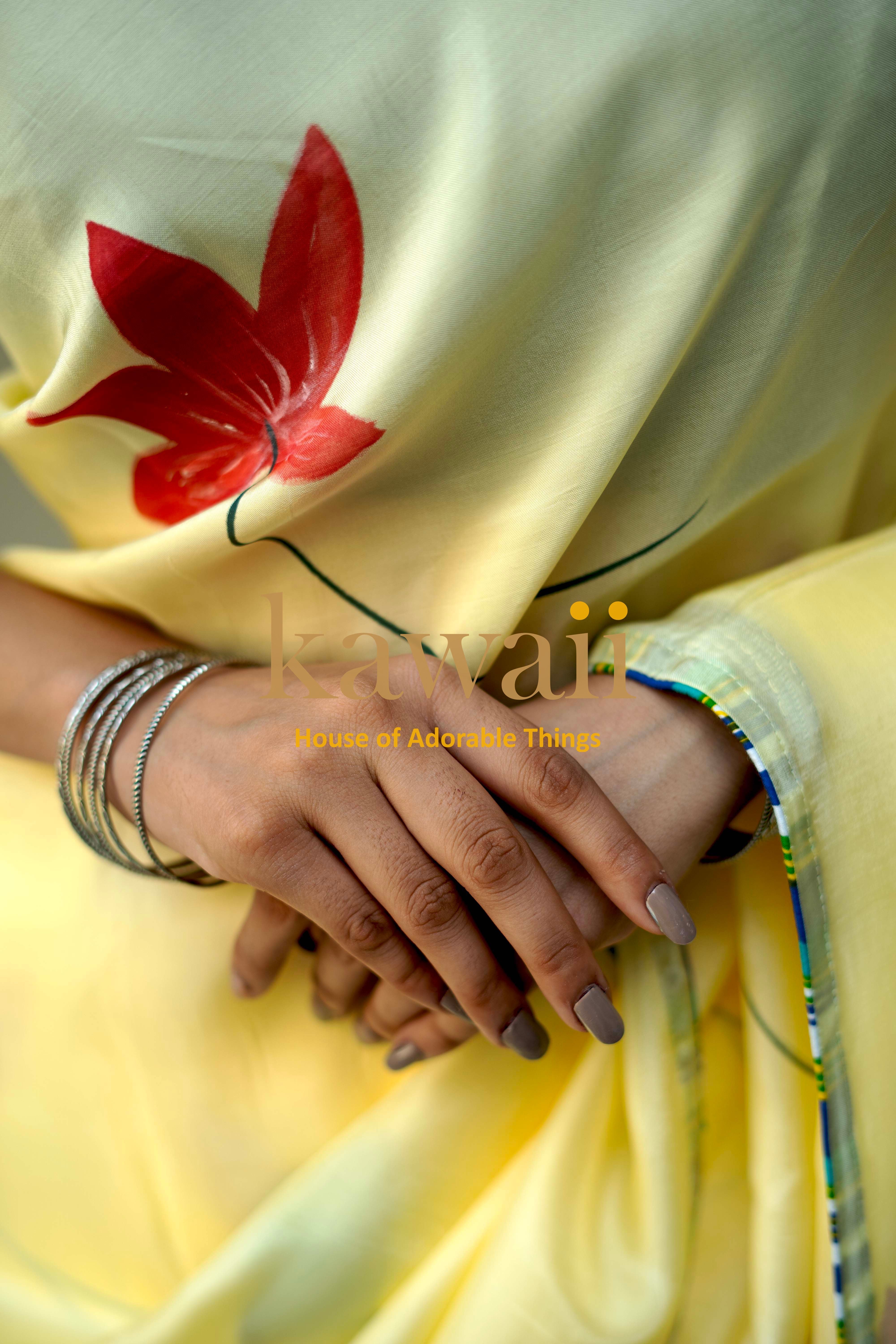 Close-up of hands wearing bangles on a yellow pichwai saree with red floral design by Kawaii