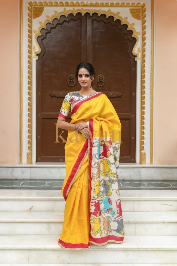 Kawaii yellow pichwai saree with multi-colored traditional design worn by woman standing on marble steps