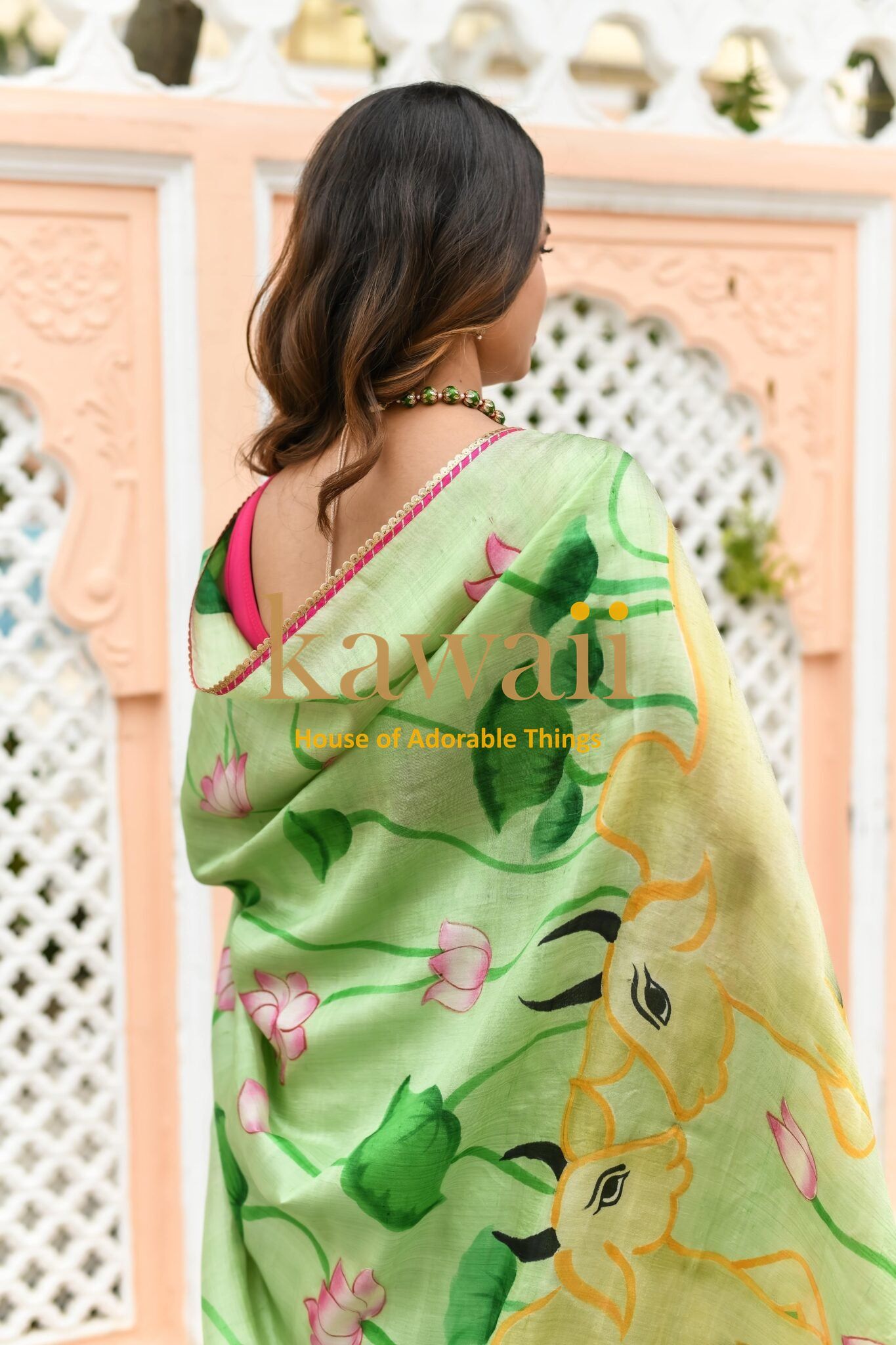 Woman wearing a green and yellow floral pichwai saree by Kawaii with pink flowers and traditional design