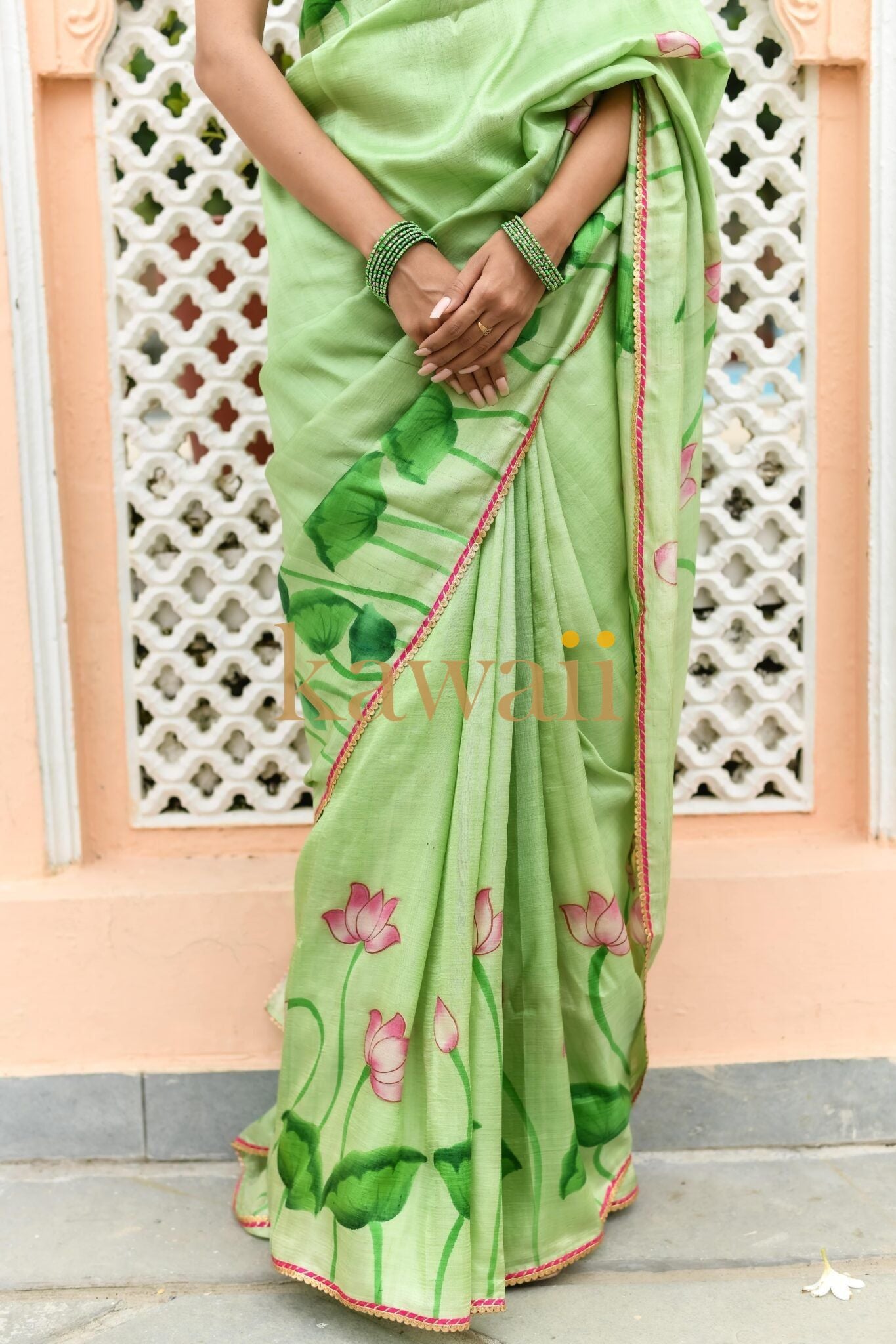 Kawaii green pichwai saree with lotus flower prints and pink border worn by woman