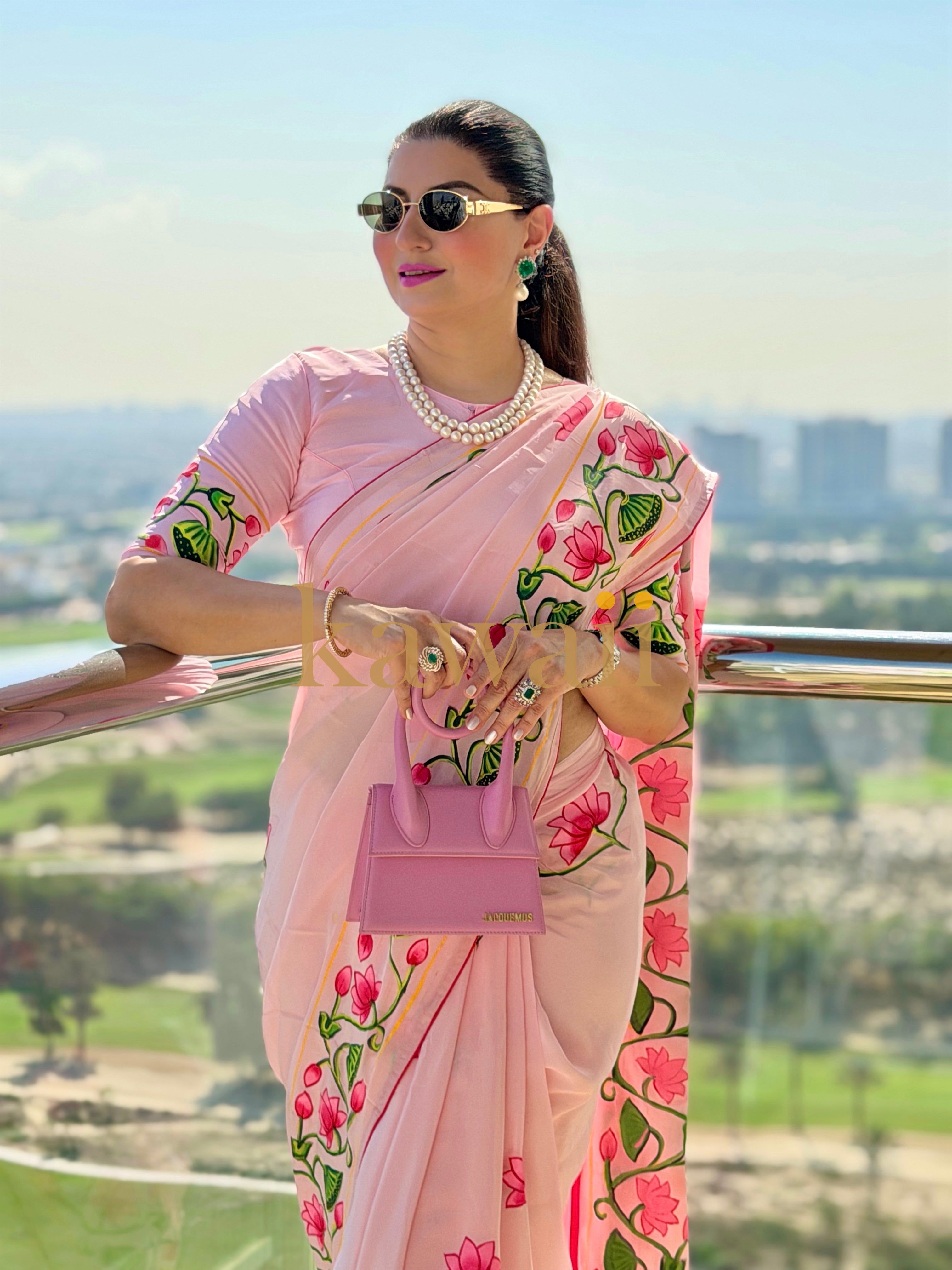 Elegant woman in a pink pichwai saree adorned with flower patterns, accessorized with sunglasses and a pearl necklace