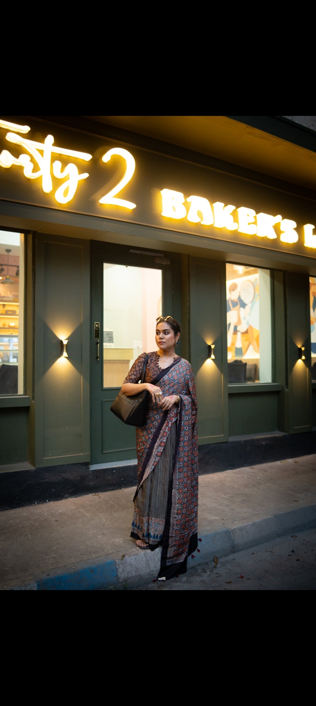 Woman wearing the best authentic ajrakh saree by Kawaii standing outside a bakery at night