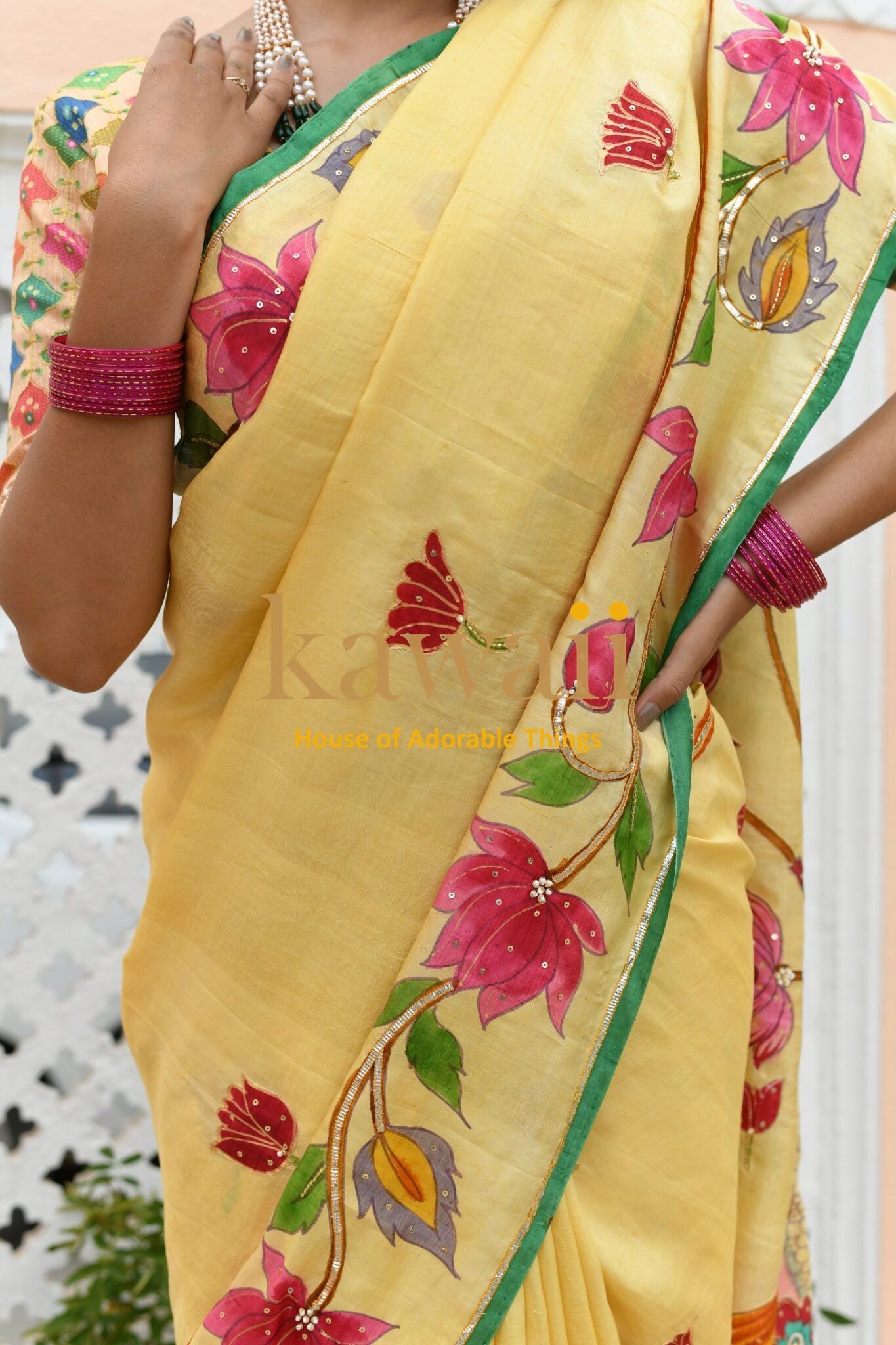 Kawaii yellow pichwai saree with pink floral embroidery and green border worn with pink bangles