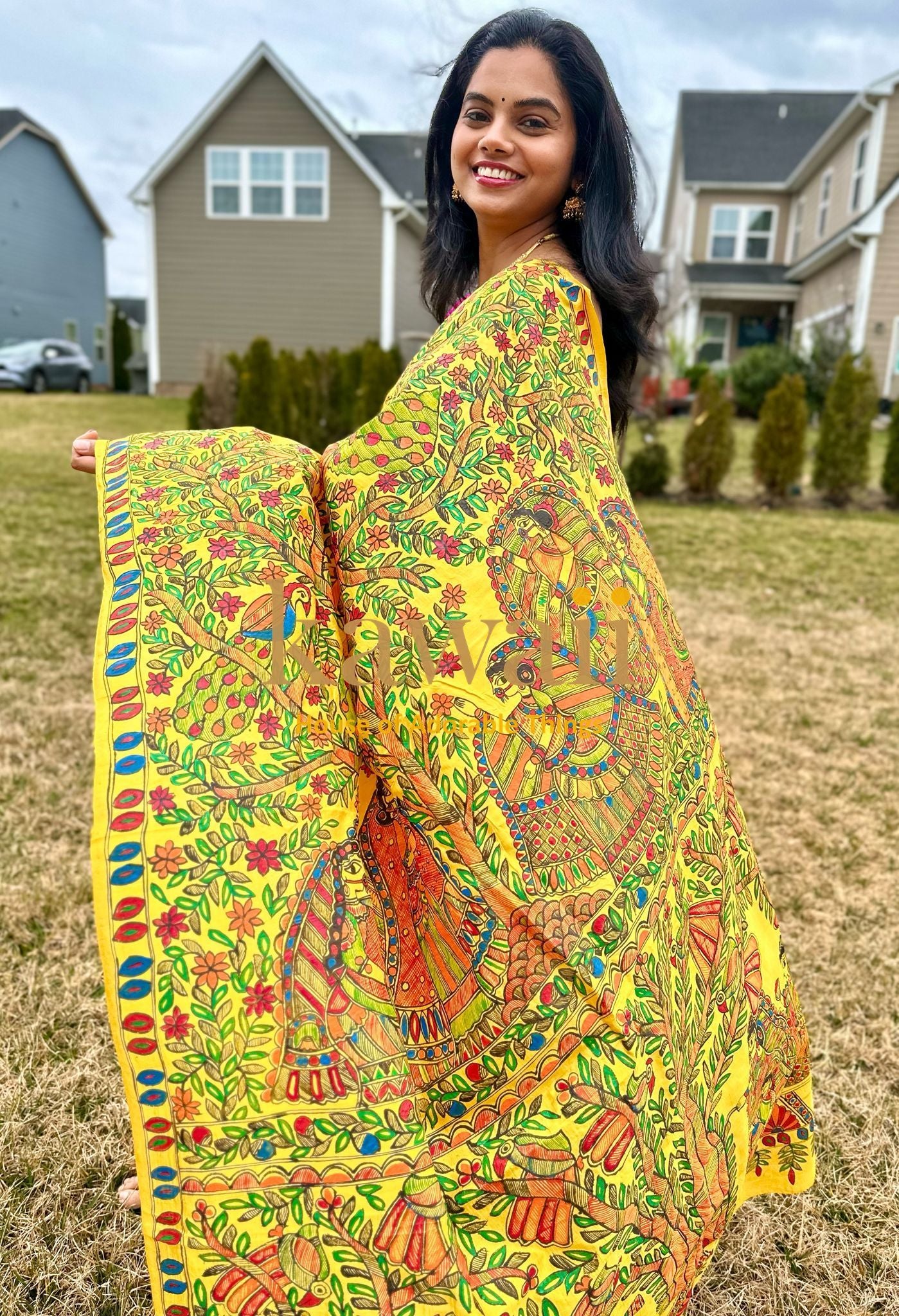 Woman wearing a vibrant yellow madhubani saree with intricate traditional artwork outdoors