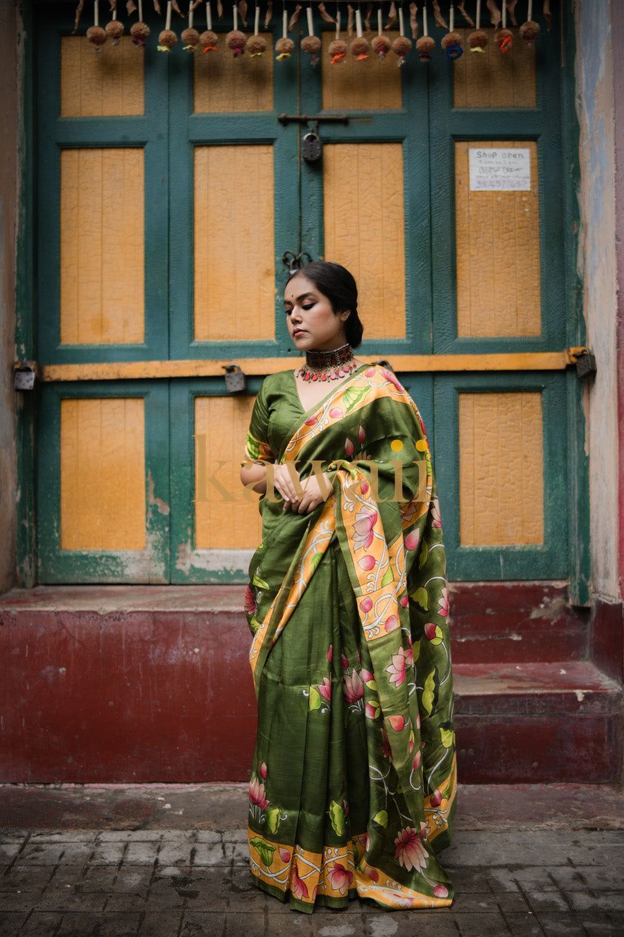Kawaii elegant green pichwai saree with floral patterns and golden border worn by a woman