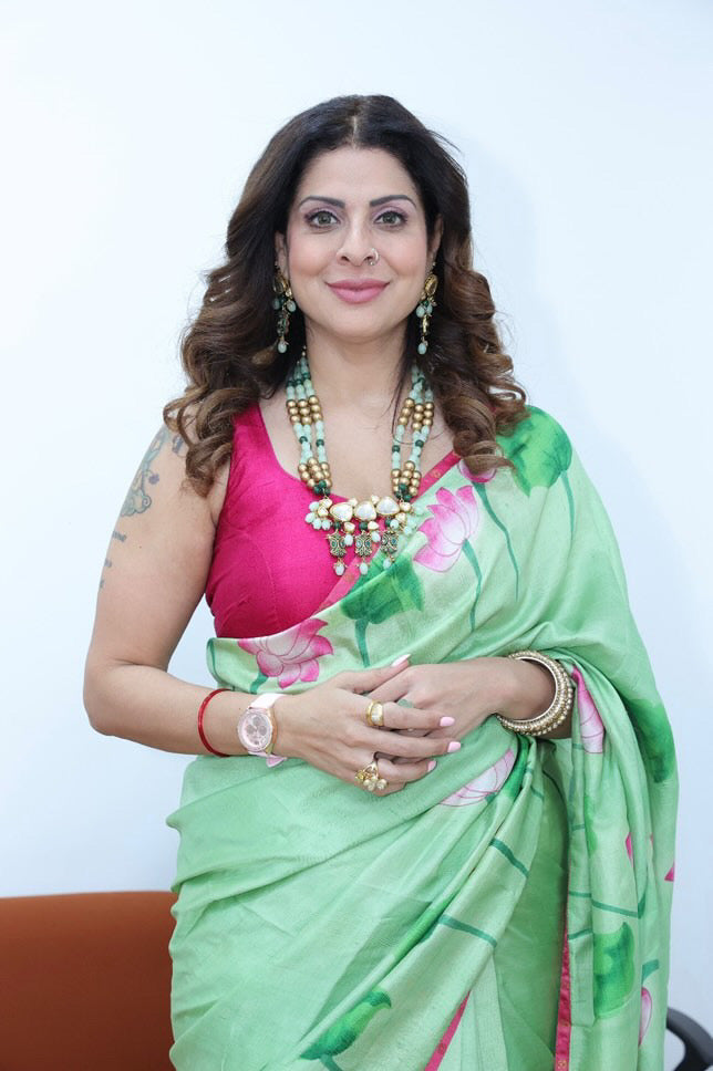 Woman wearing green floral pichwai saree with pink blouse and traditional jewelry