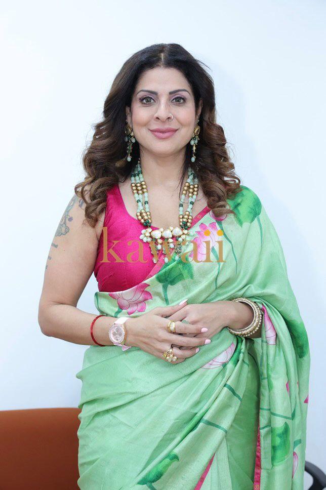 Elegant pichwai saree in soft green with pink floral patterns, paired with traditional jewelry