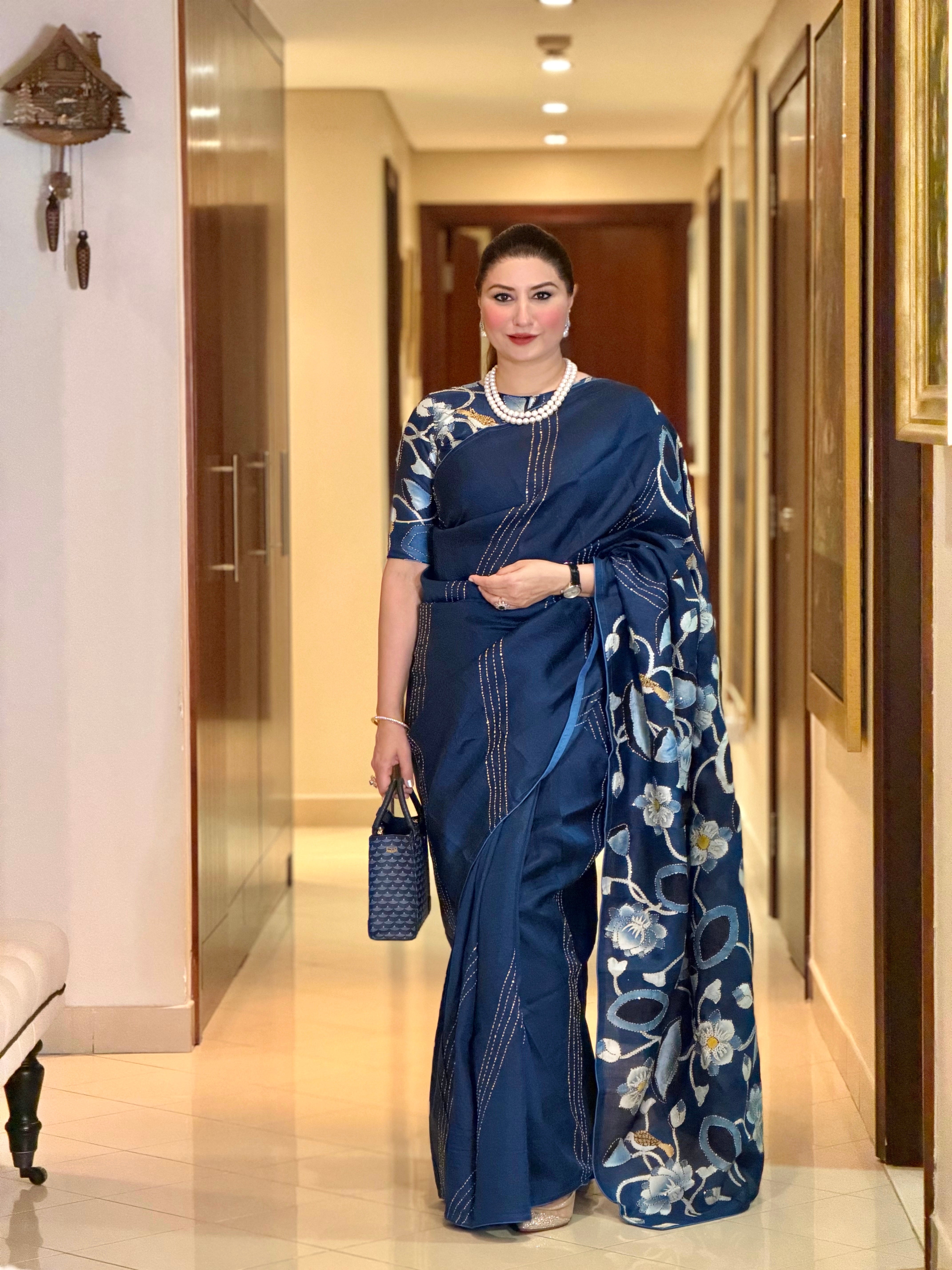 Elegant woman wearing a blue pichwai saree with intricate floral designs and a matching blouse