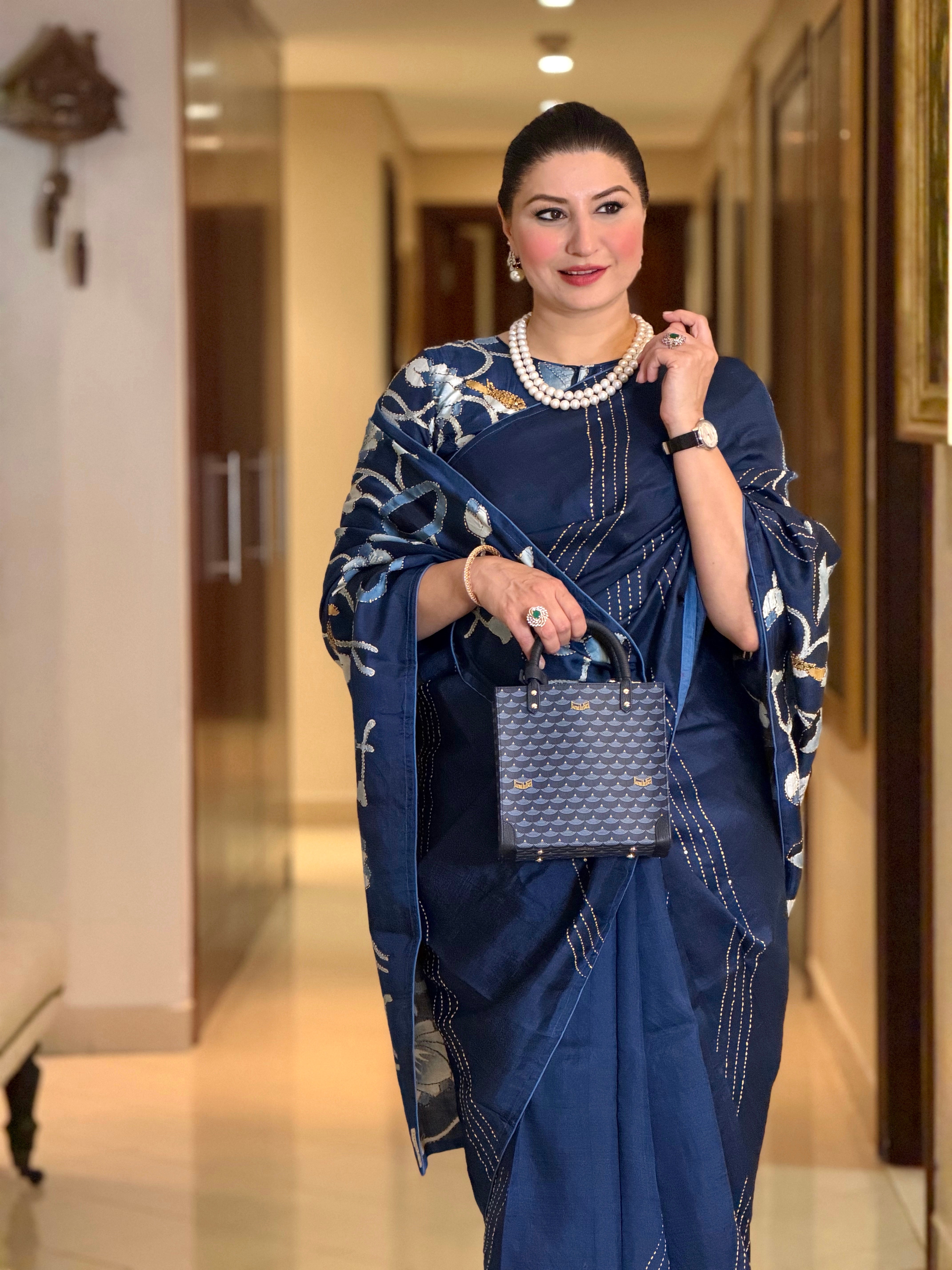 Elegant woman wearing a pichwai saree in navy with floral design and stylish handbag for a formal look