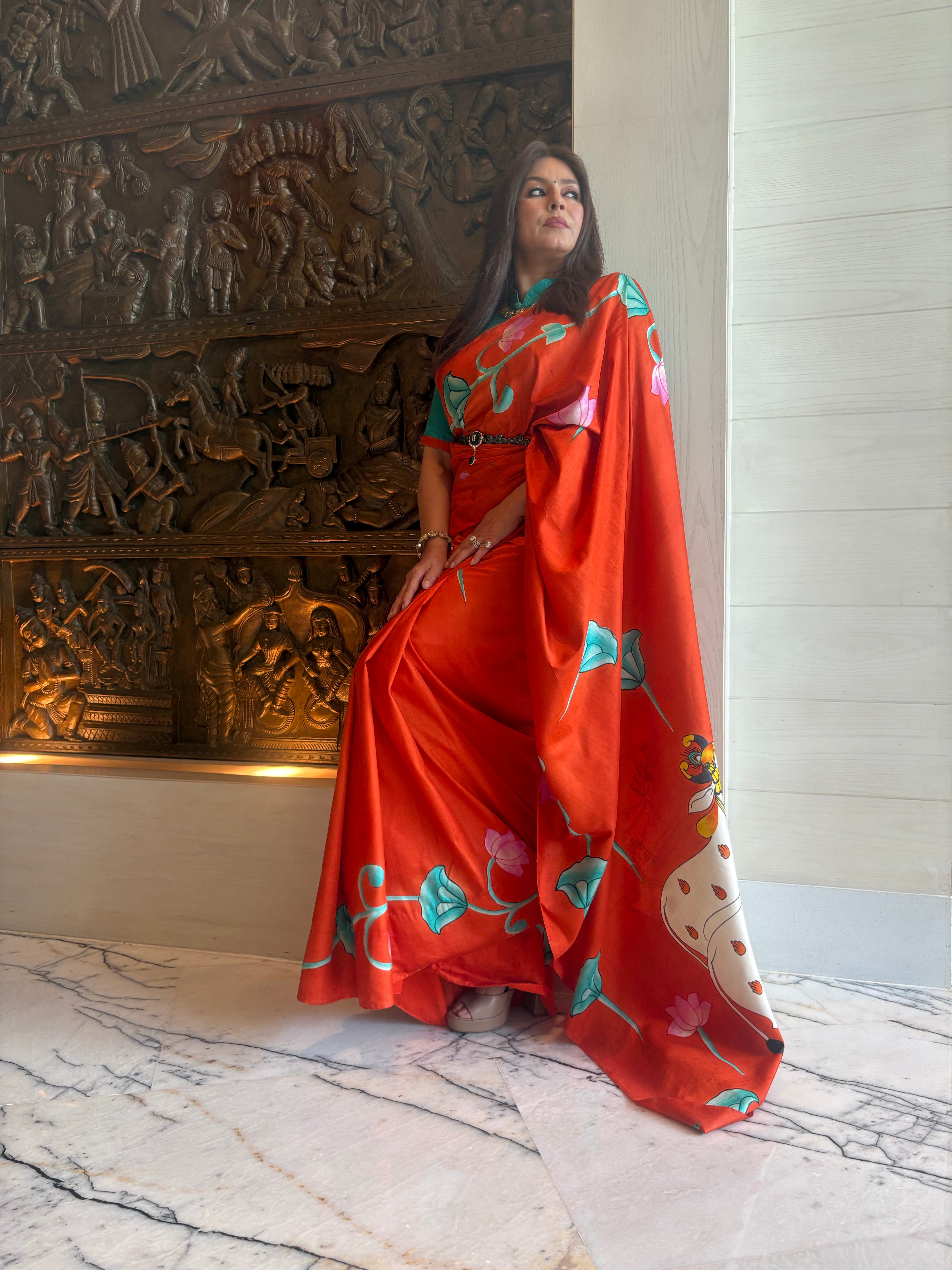 Elegant model wearing a vibrant pichwai saree with floral motifs and rich colors in a stylish setting
