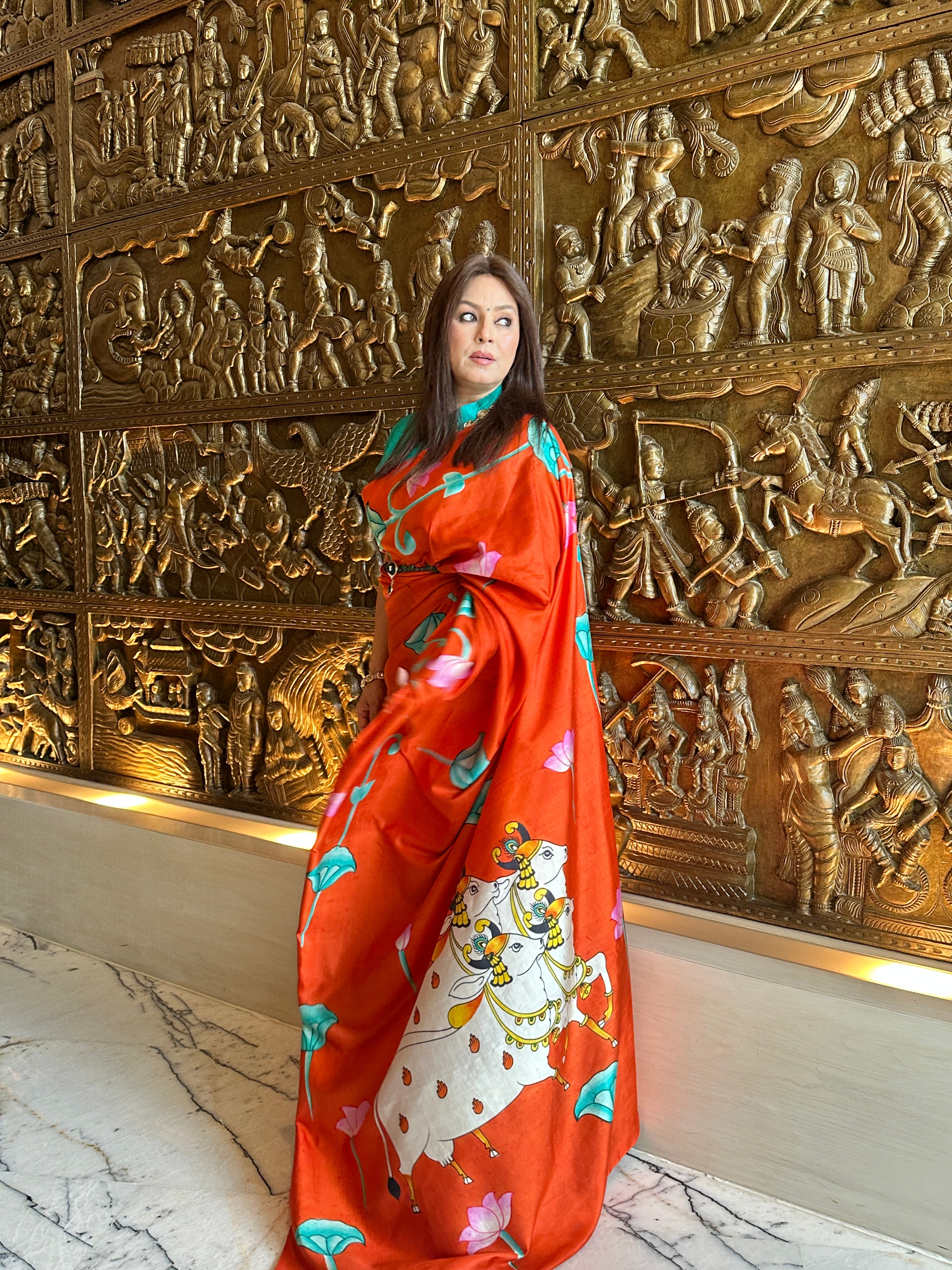 Elegant Pichwai Saree in vibrant orange with intricate floral patterns and traditional artwork