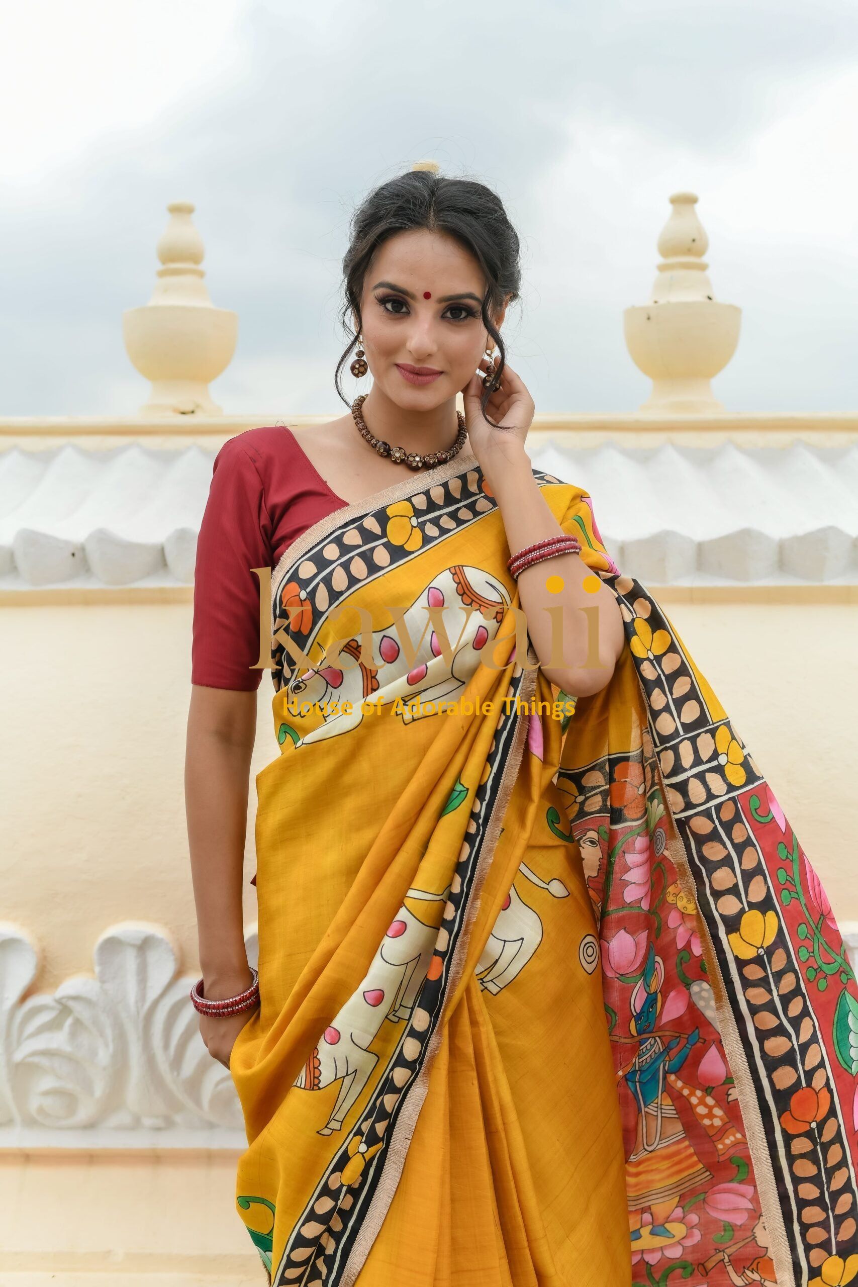 Kawaii pichwai saree in mustard yellow with traditional intricate artwork worn by a woman with maroon blouse