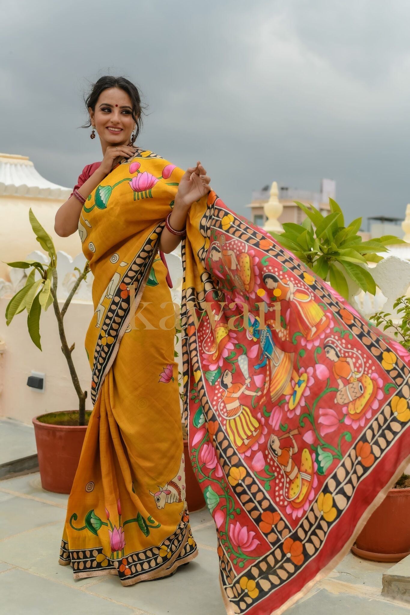 Elegant yellow pichwai saree with vibrant hand-painted motifs featuring deities and floral designs.