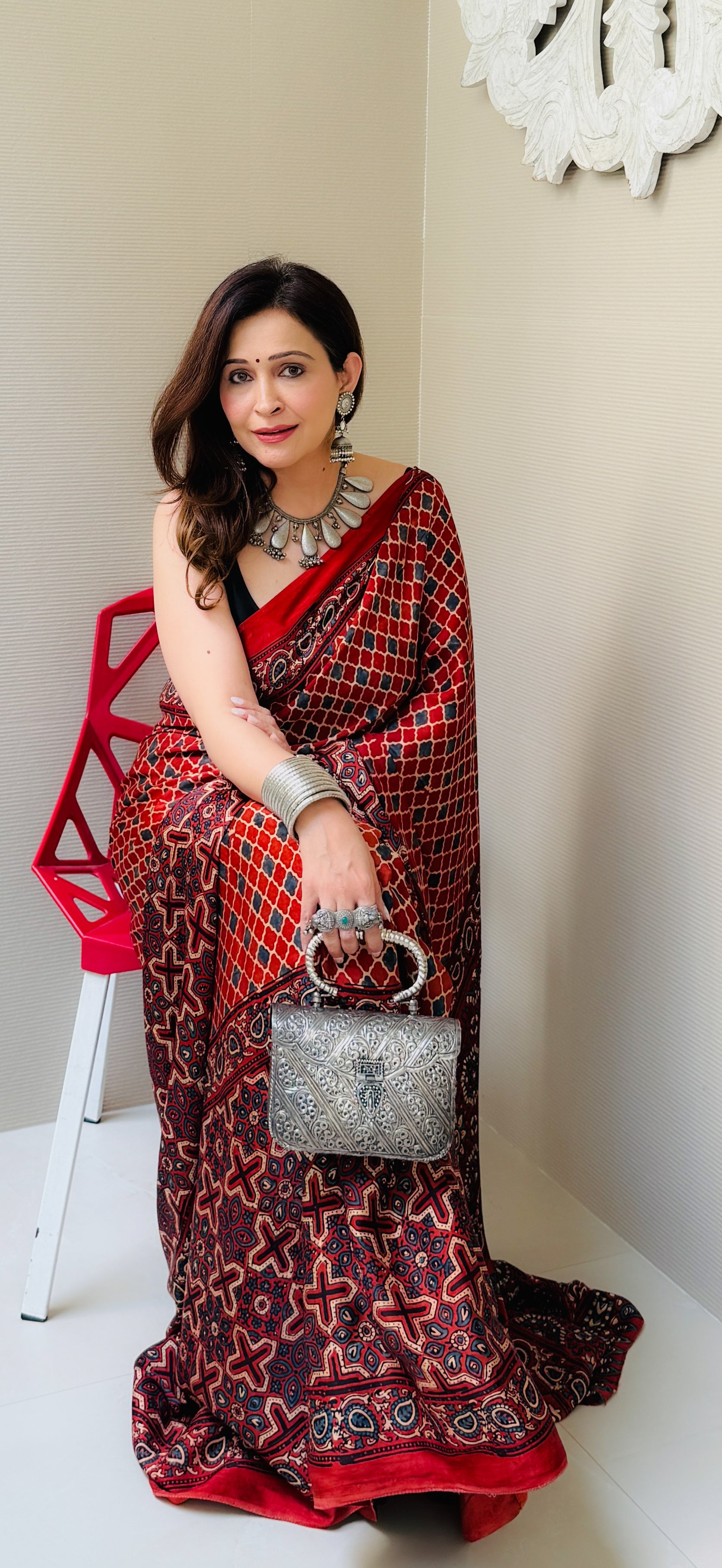Kawaii ajrakh saree in red and black geometric patterns worn with silver jewelry and matching handbag