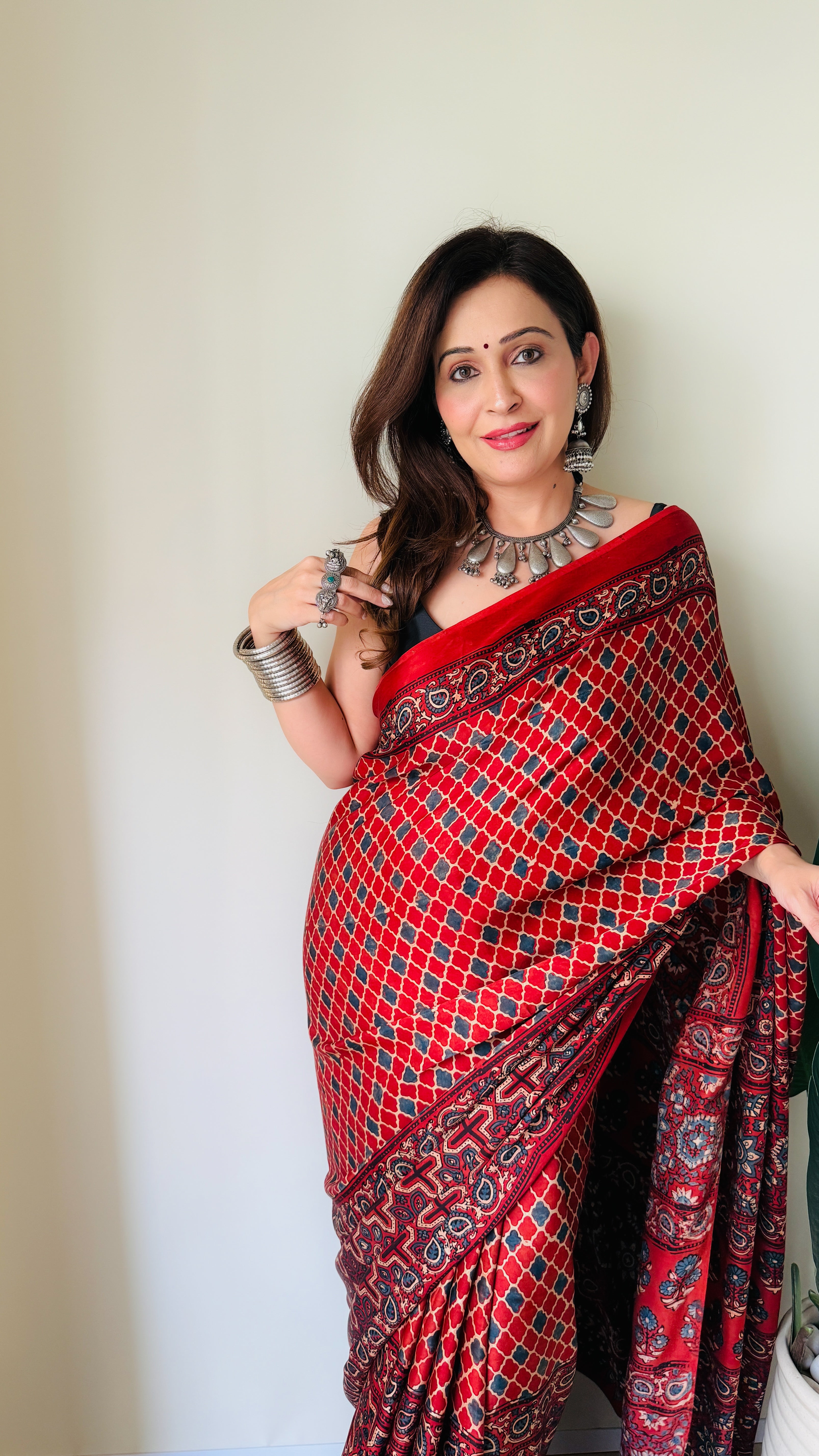 Woman wearing a red ajrakh saree with intricate patterns and traditional silver jewelry